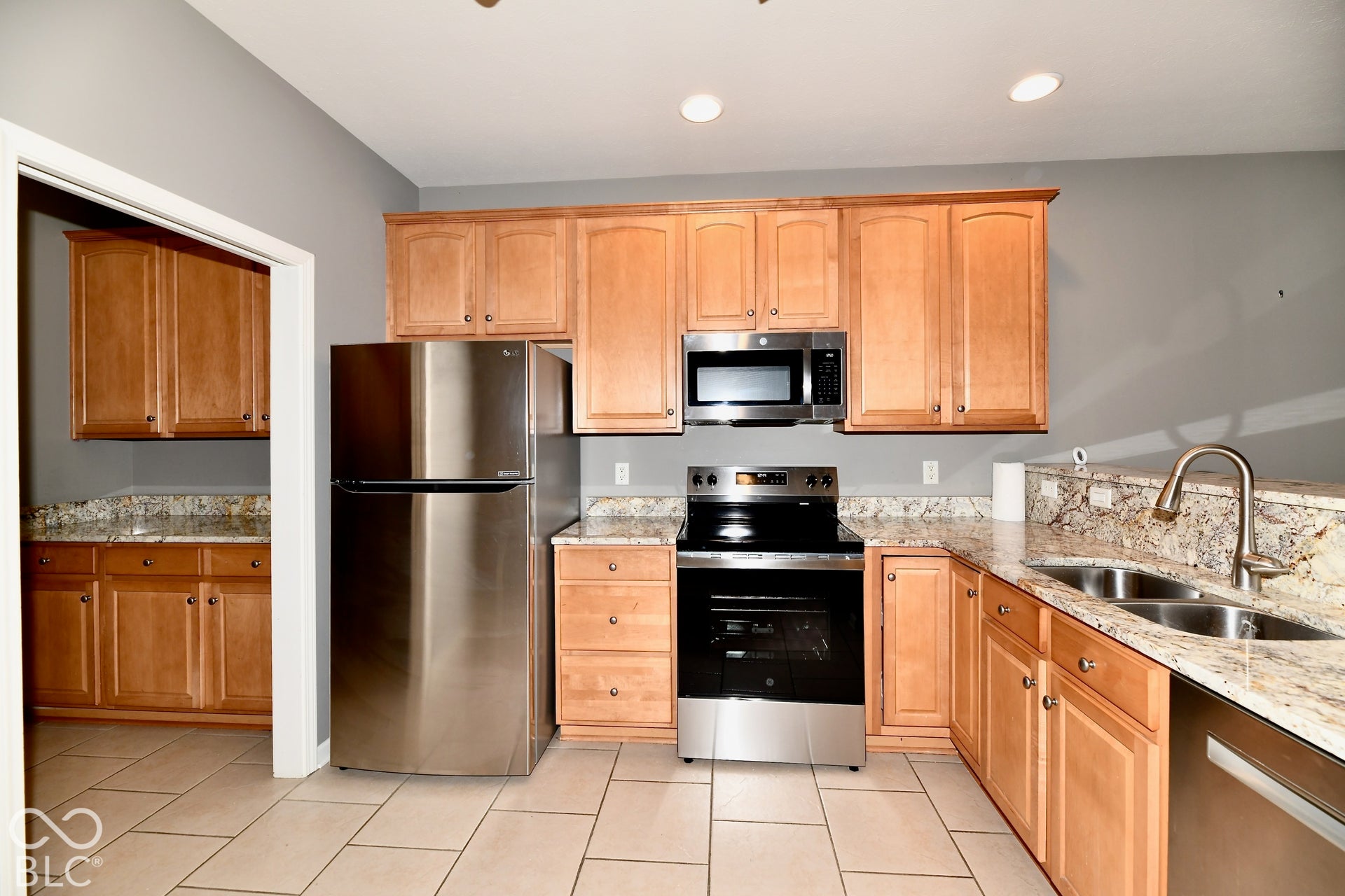 6673 Avila Way, Fishers, IN 46038 Kitchen featuring wood-finish cabinetry, stainless steel appliances, dual basin sink, pull-down faucet, and granite countertops