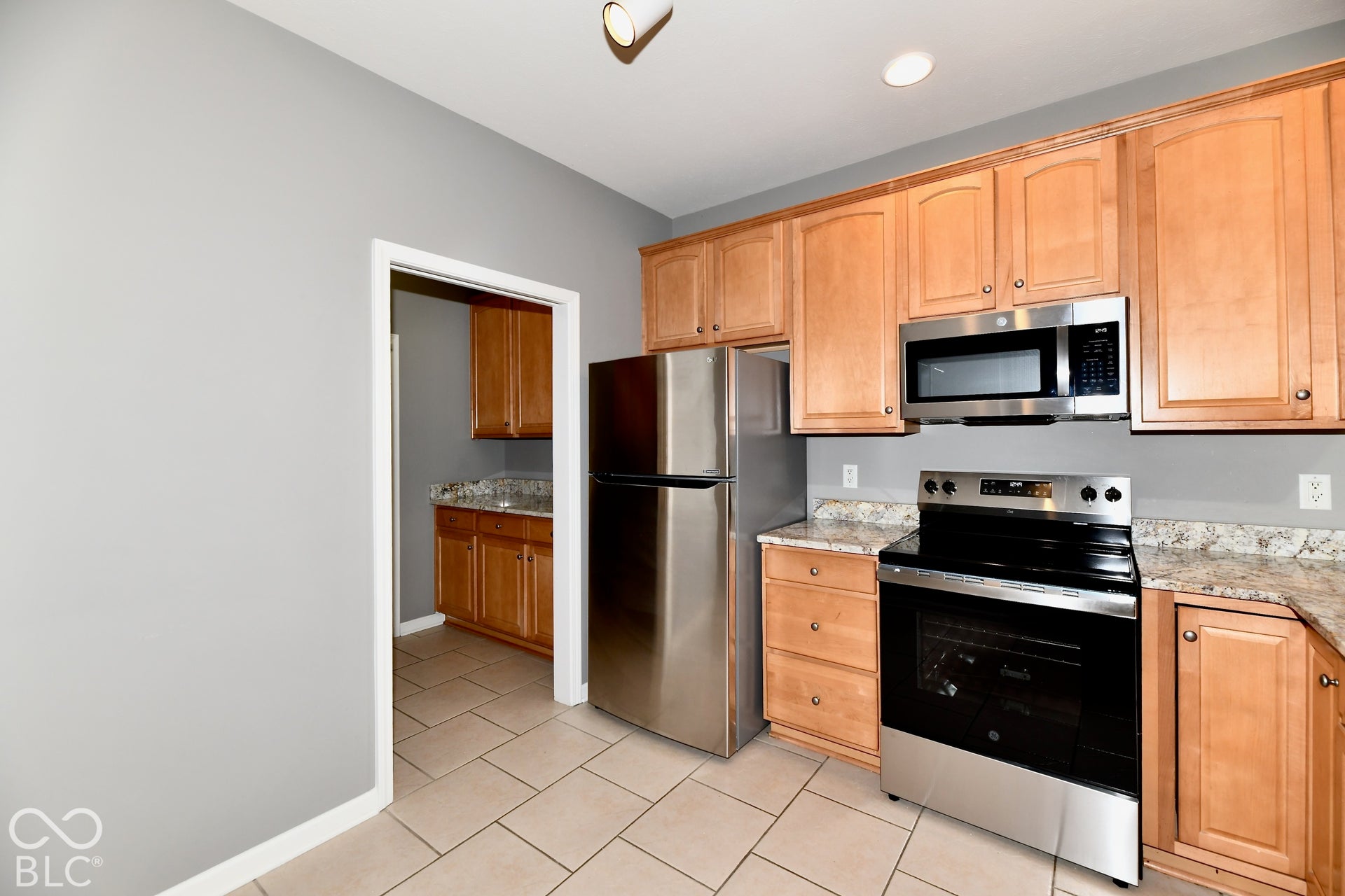6673 Avila Way, Fishers, IN 46038 Kitchen featuring light wood cabinetry, stainless steel appliances, granite countertops, and neutral tile flooring