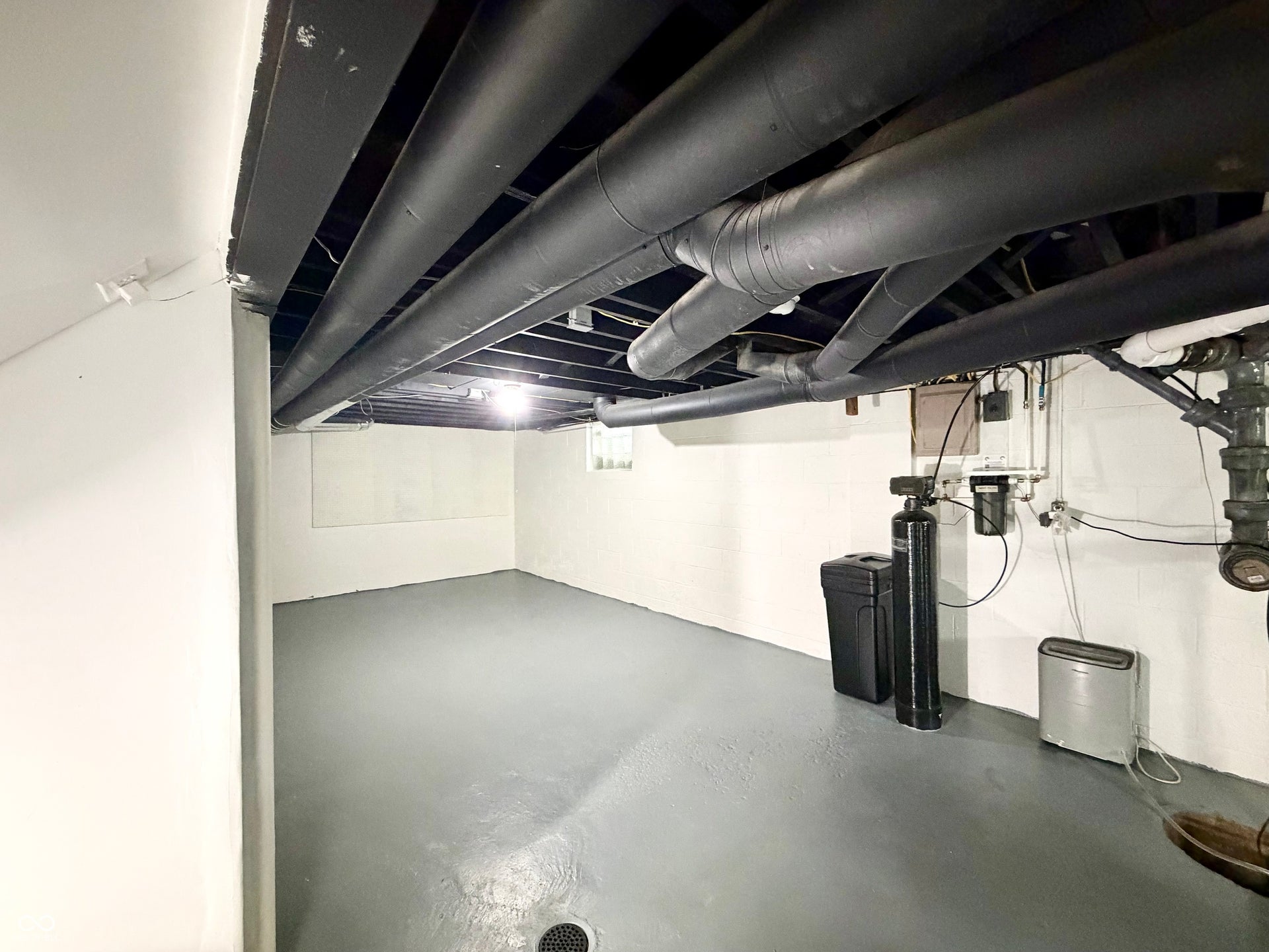 6314 N Keystone Avenue, Indianapolis, IN 46220 Utility room featuring painted concrete flooring, white walls, and an exposed ceiling with black-painted beams and ductwork