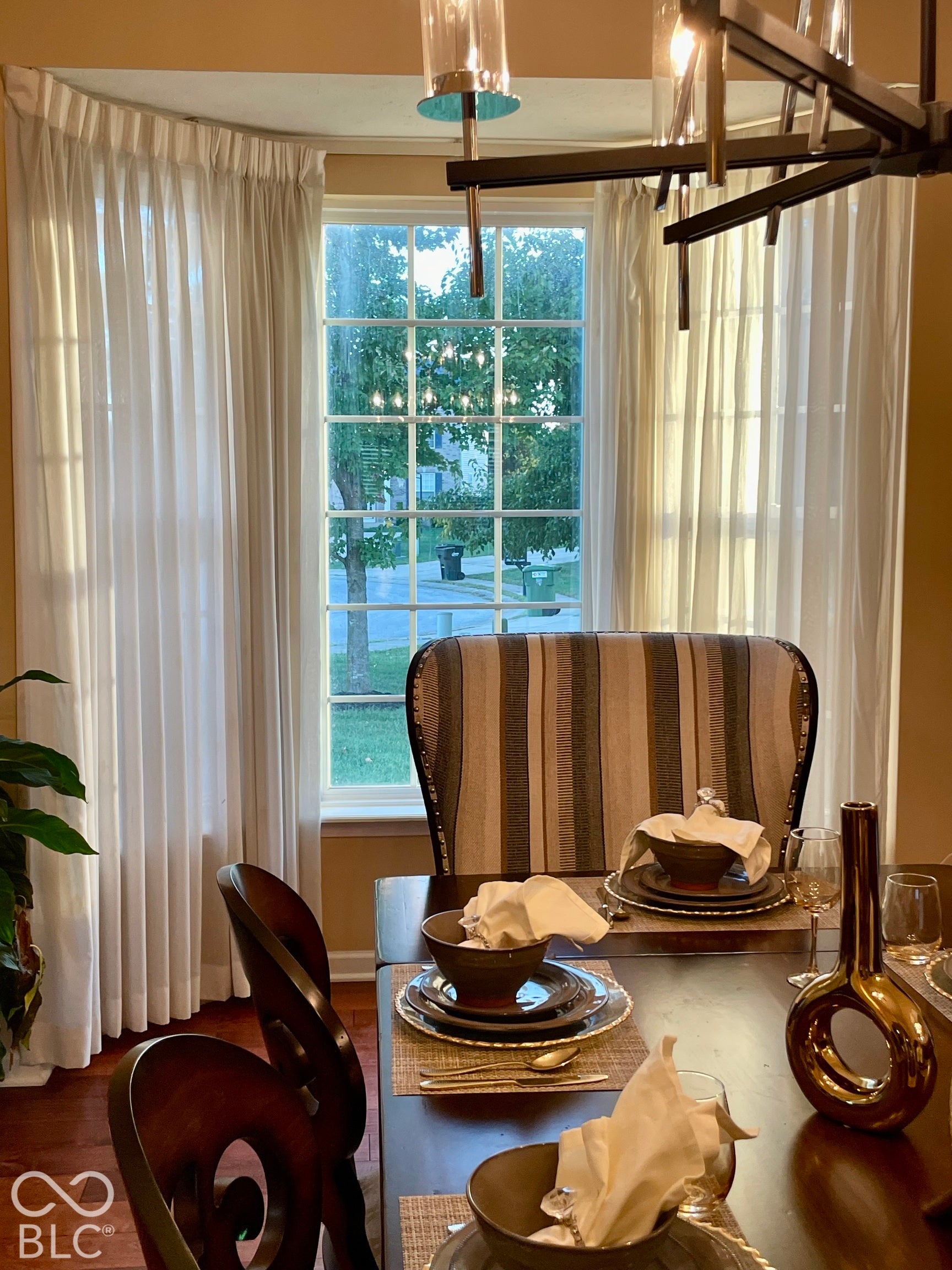 Bay window with grid-patterned panes, wood-finish flooring, and a contemporary multi-light chandelier