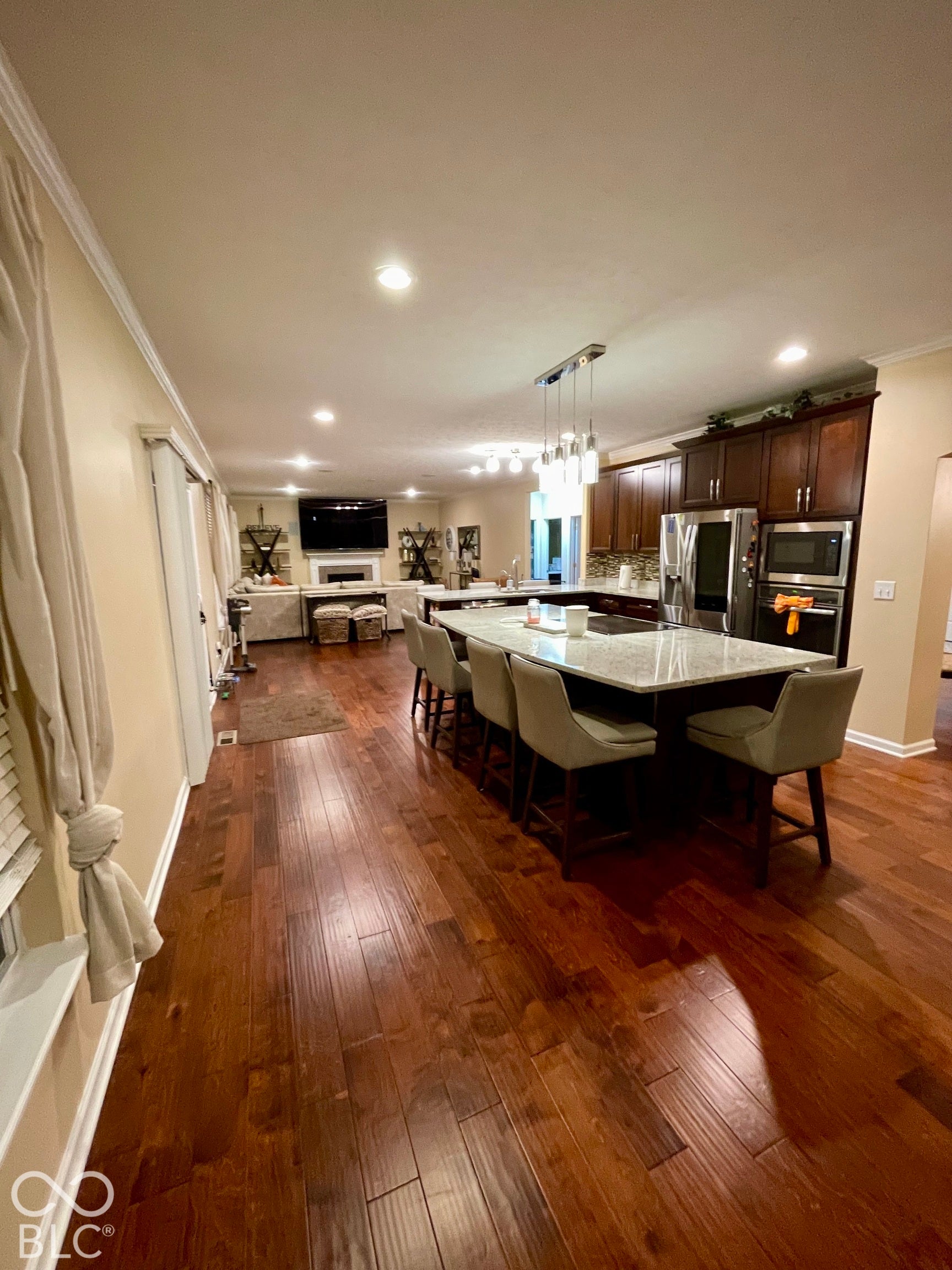 Expansive kitchen with a large island, stainless steel appliances, dark wood-finish cabinetry, and wood-finish flooring