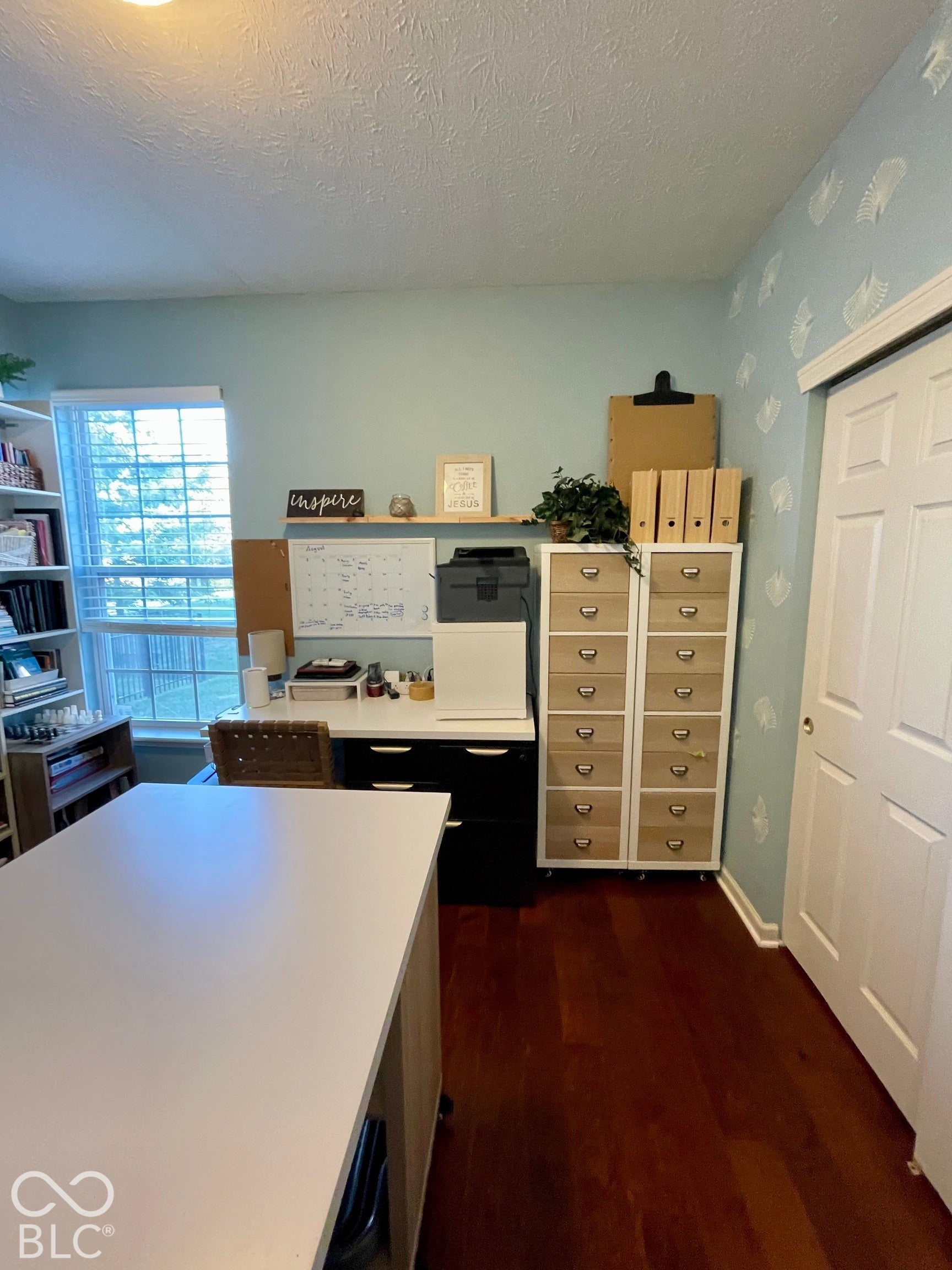 Wood-finish flooring, built-in shelving, natural light from a window, and a light-colored wall finish