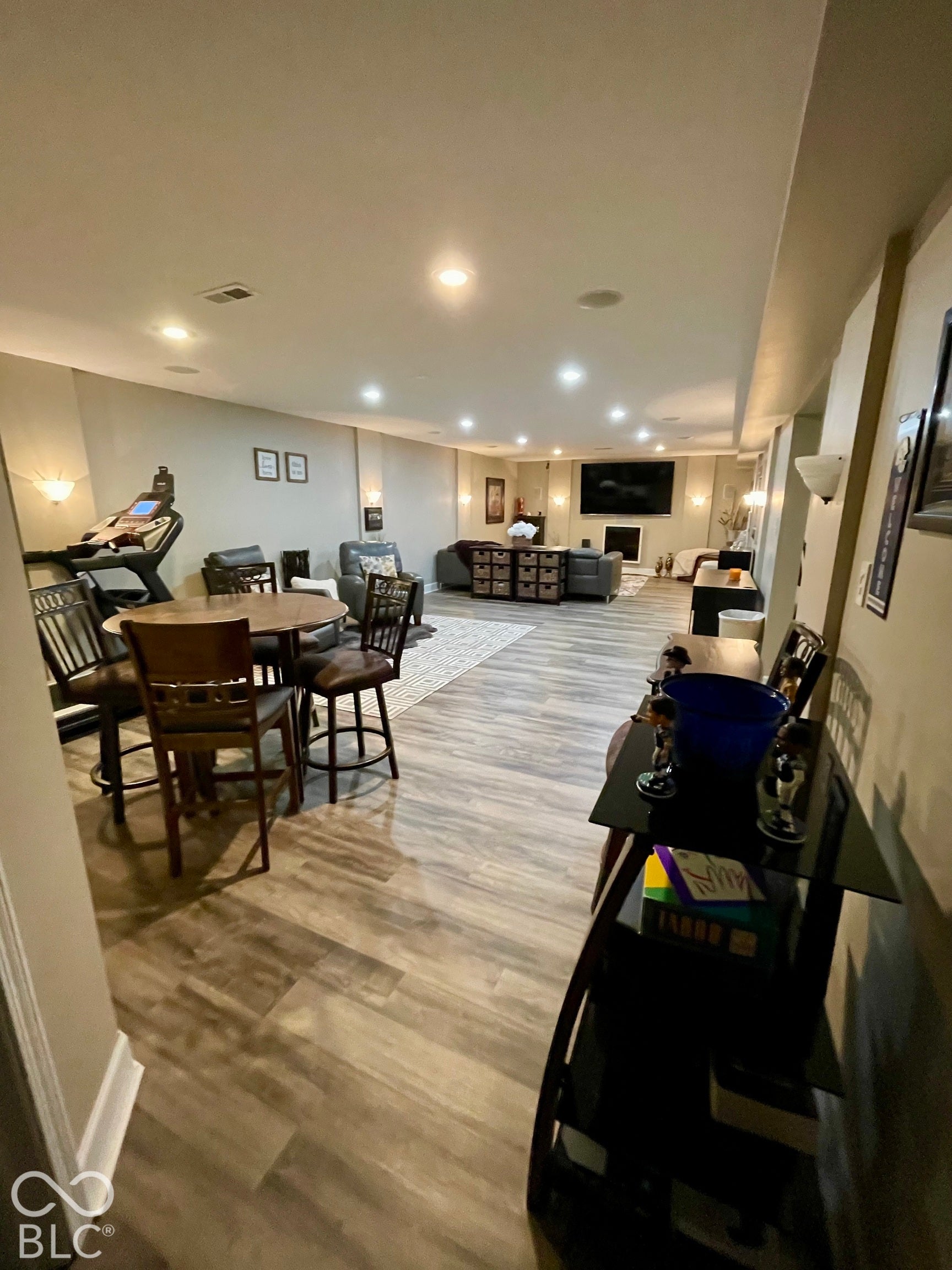 Spacious open-concept room featuring wood-finish flooring, recessed lighting, and wall sconces