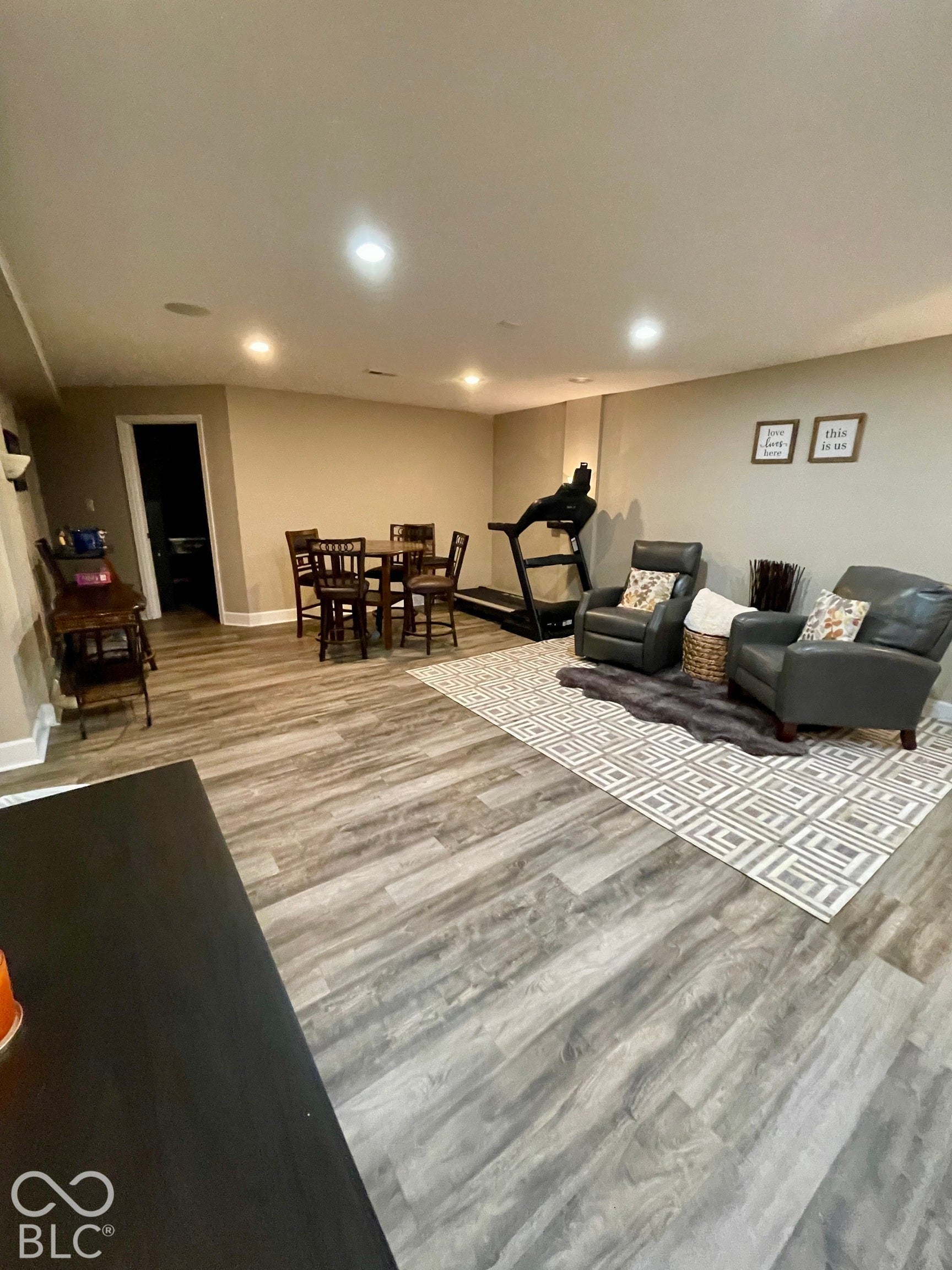 Recessed lighting, wood-finish flooring, neutral wall tones, white trim, and a paneled interior door