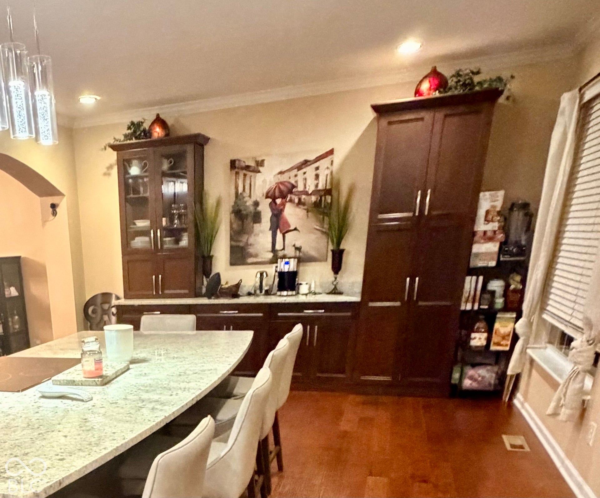 Built-in cabinetry with glass-front uppers, light-toned countertop, and wood-finish flooring