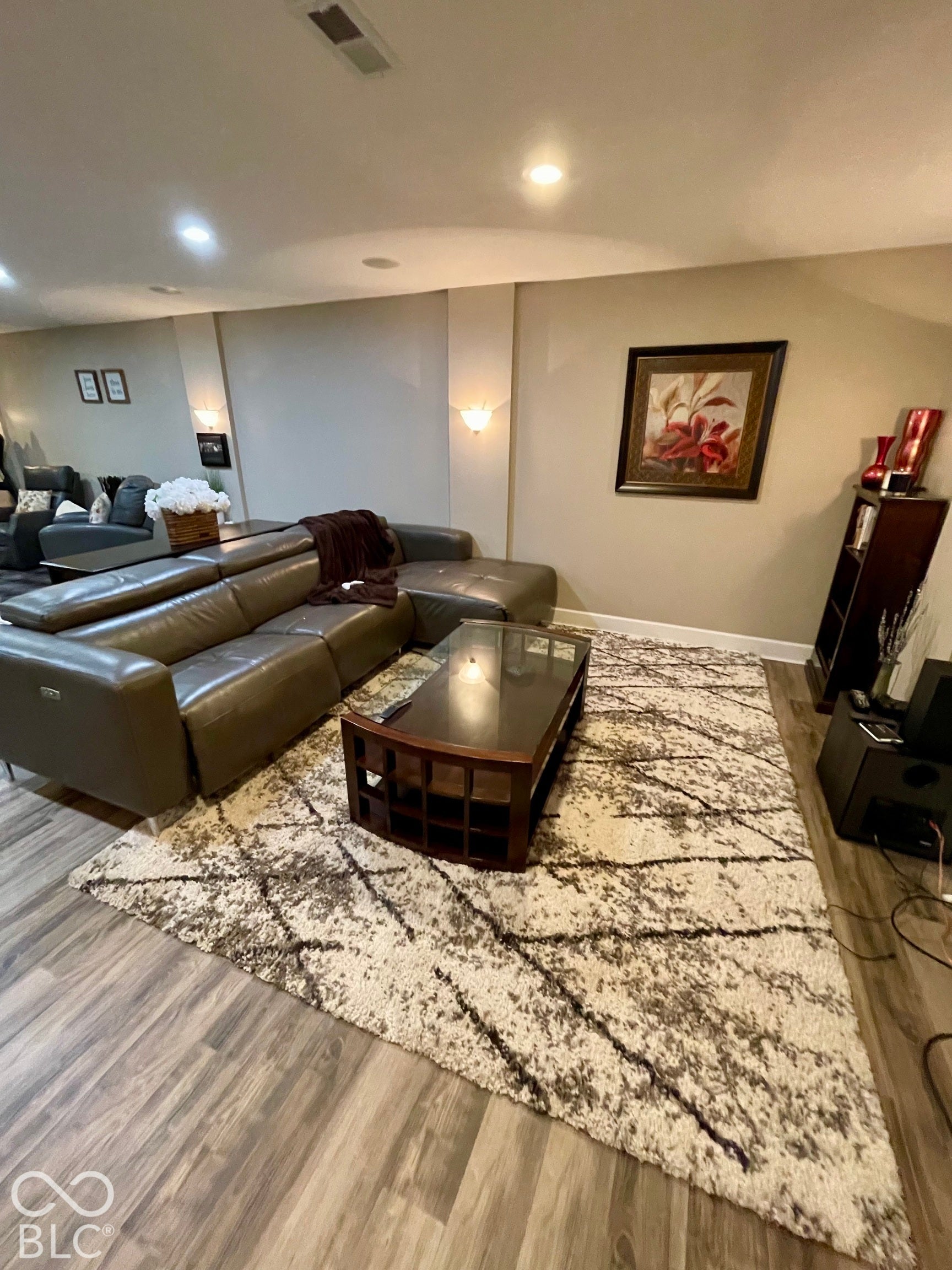 Recessed ceiling lighting, wood-finish flooring, and wall-mounted sconce lighting