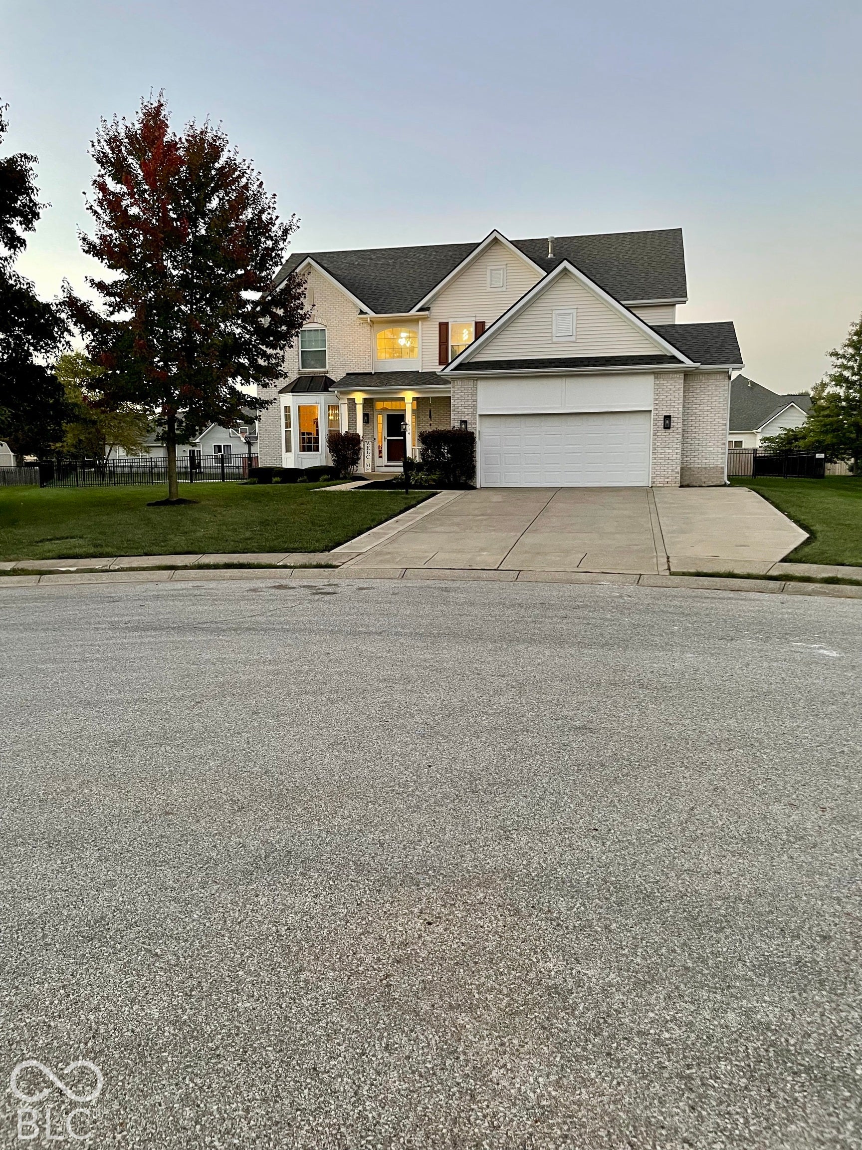 Two-story residence featuring light-colored brick and siding, a two-car garage, and a concrete driveway