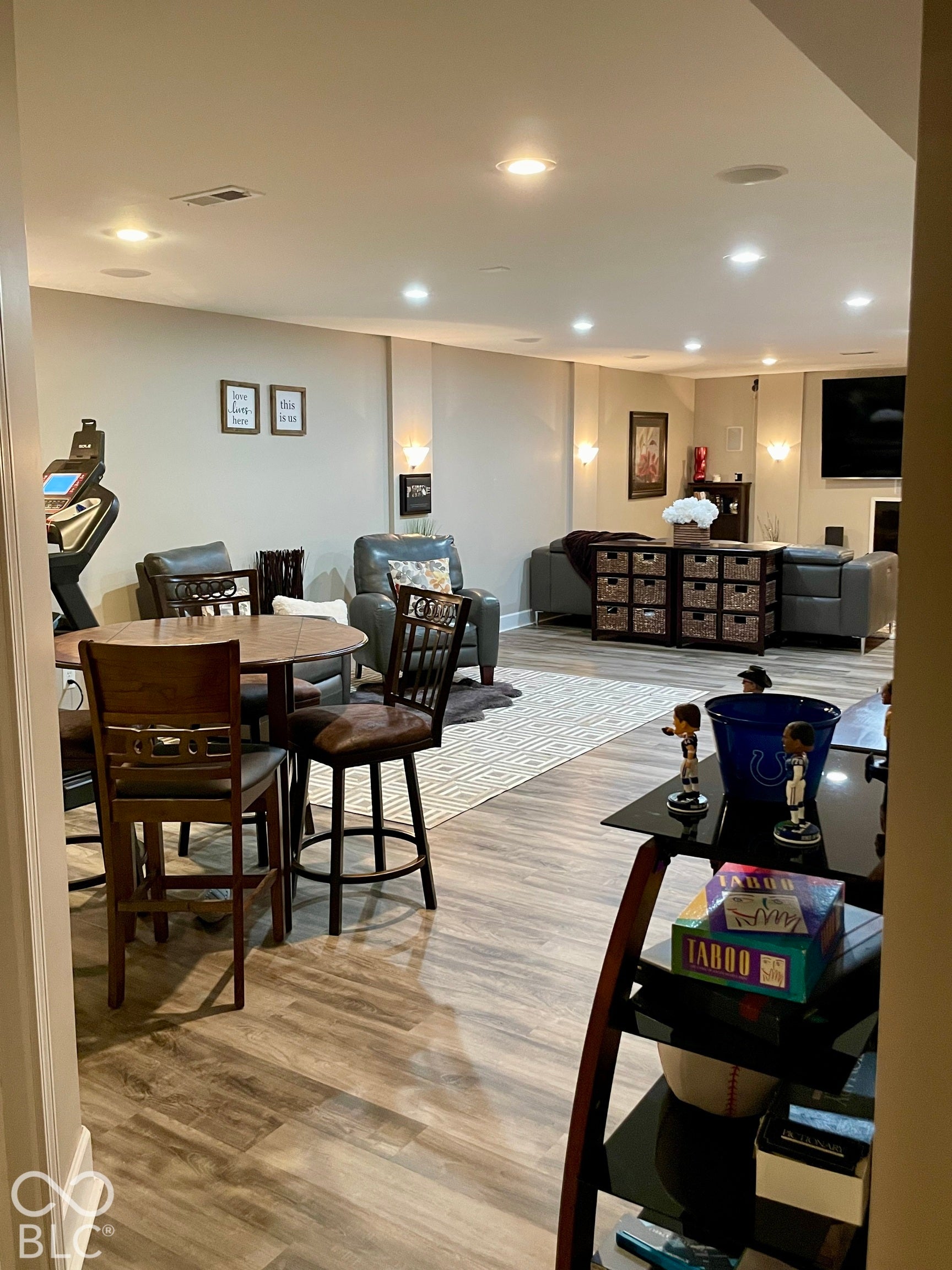Recessed lighting, wood-finish flooring, accent wall sconces, ceiling-mounted speakers, and an entertainment zone
