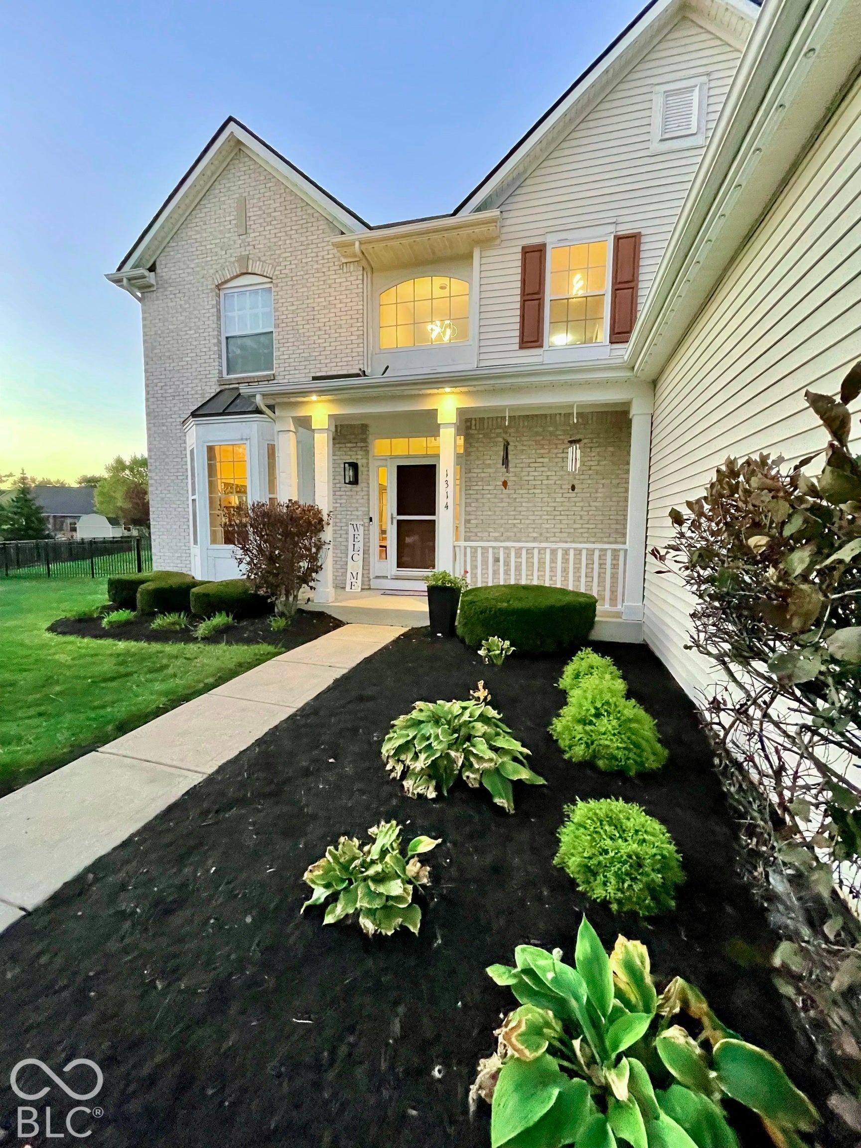 Brick and siding exterior with a covered porch, bay window, and a sidewalk leading to the entrance