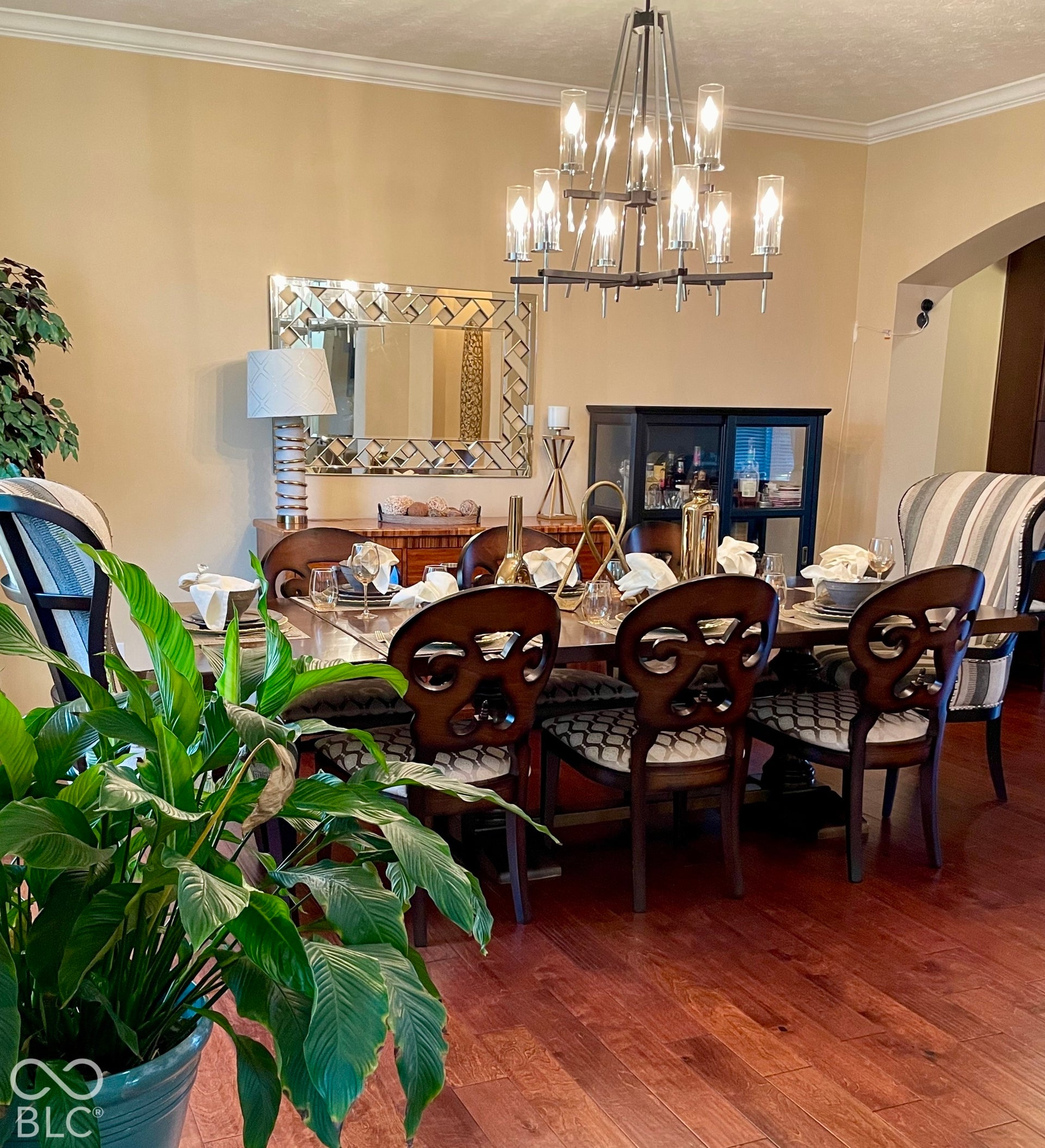 Hardwood-finish flooring, crown molding, and a contemporary chandelier illuminate this cozy dining area