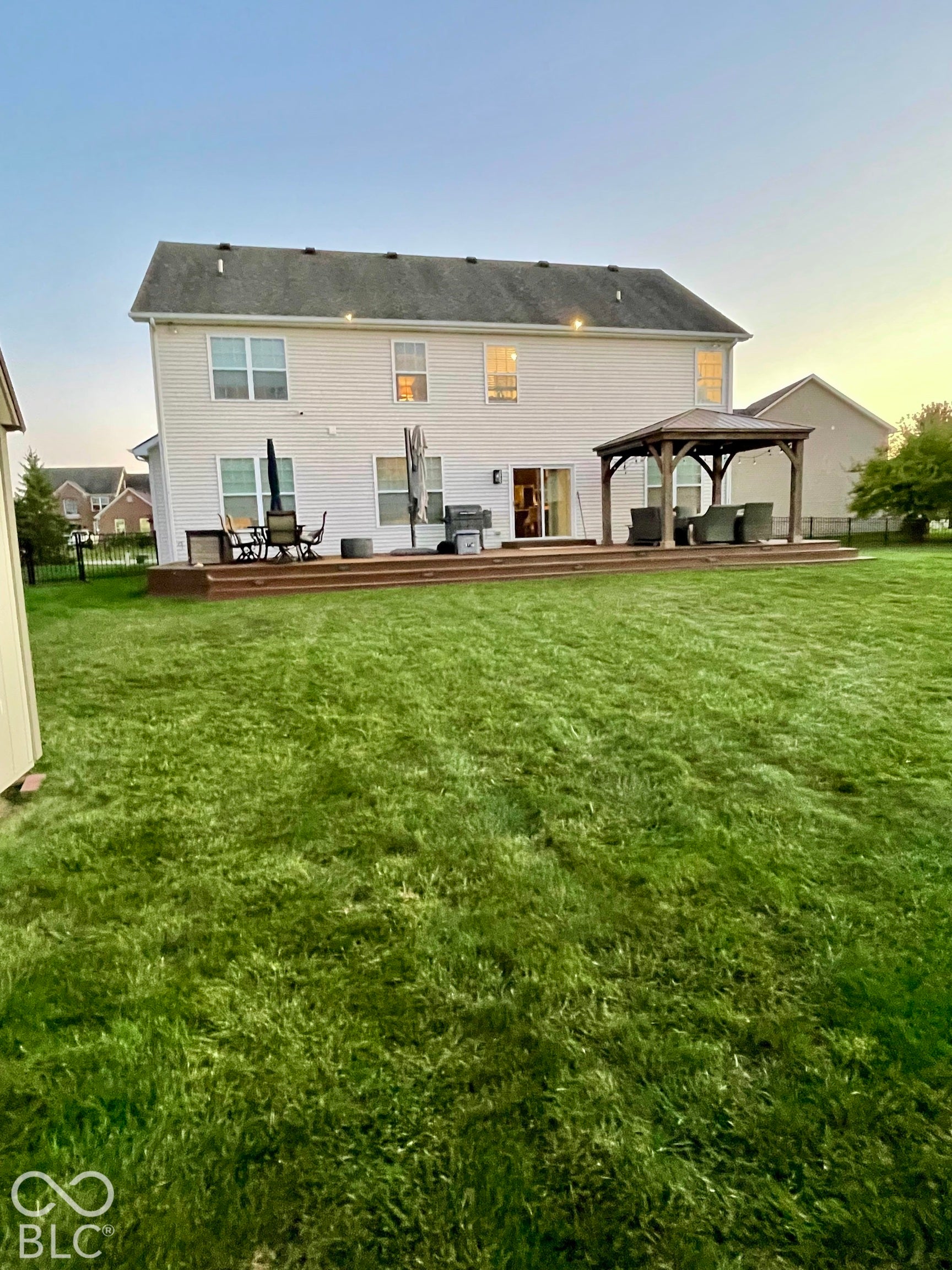 Expansive backyard featuring a manicured lawn, a large wood-finish deck, a substantial gazebo, and a siding exterior