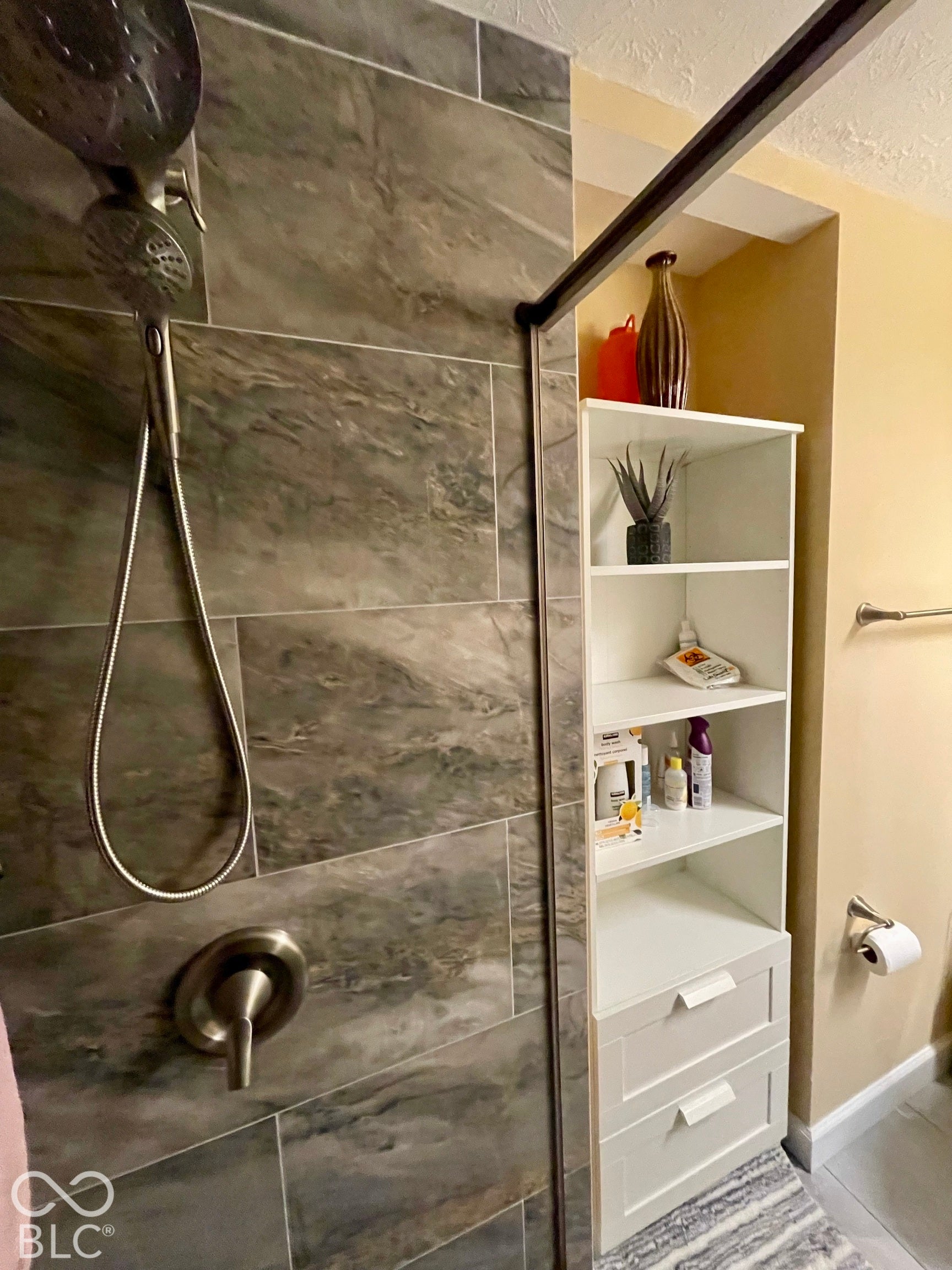 Shower with large format stone-look tile, brushed nickel fixtures, and built-in white shelving with drawers...Hall Bath
