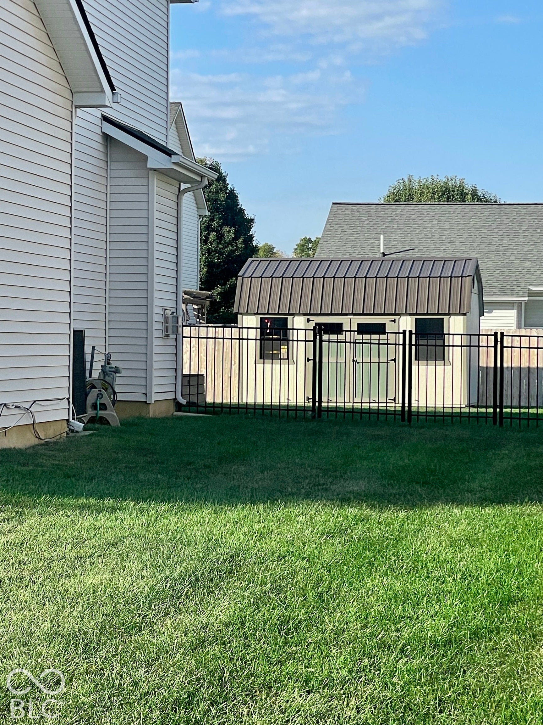 Fenced yard with a storage shed featuring a metal roof