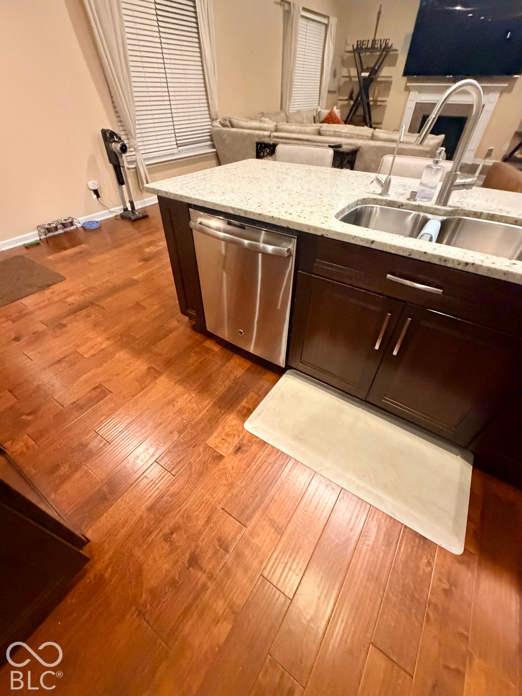 Kitchen island featuring a stainless steel sink, a stainless steel dishwasher, and a light-toned countertop