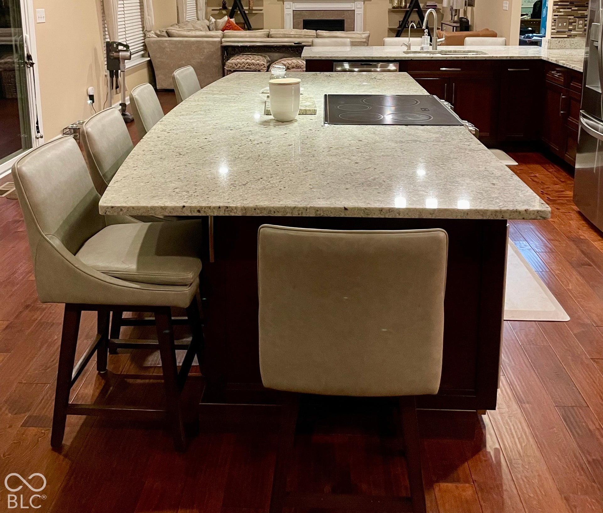 Large kitchen island featuring a smooth cooktop, ample countertop space, and rich wood-finish flooring