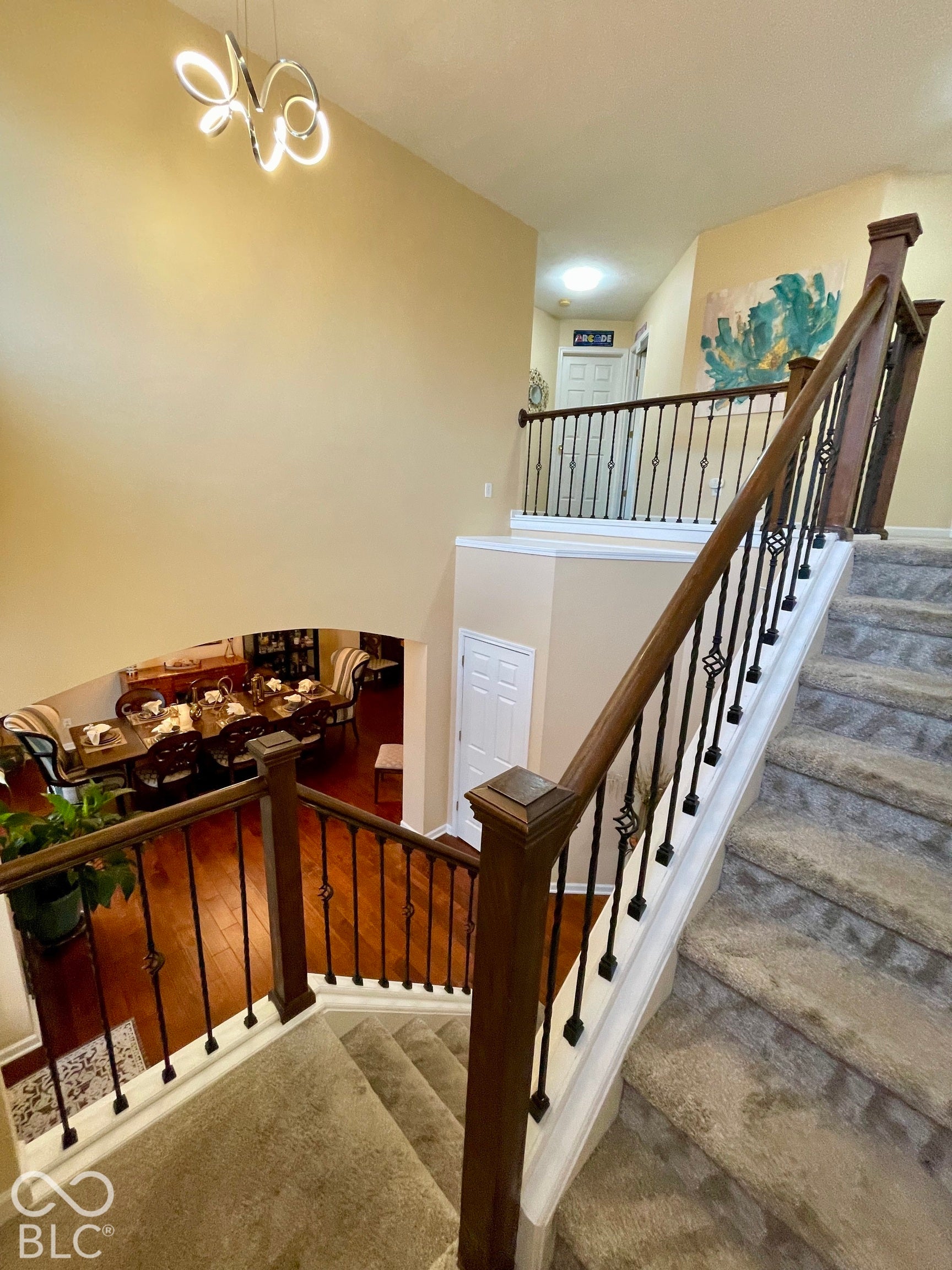 Carpeted stairway with dark wood handrails and wrought iron balusters