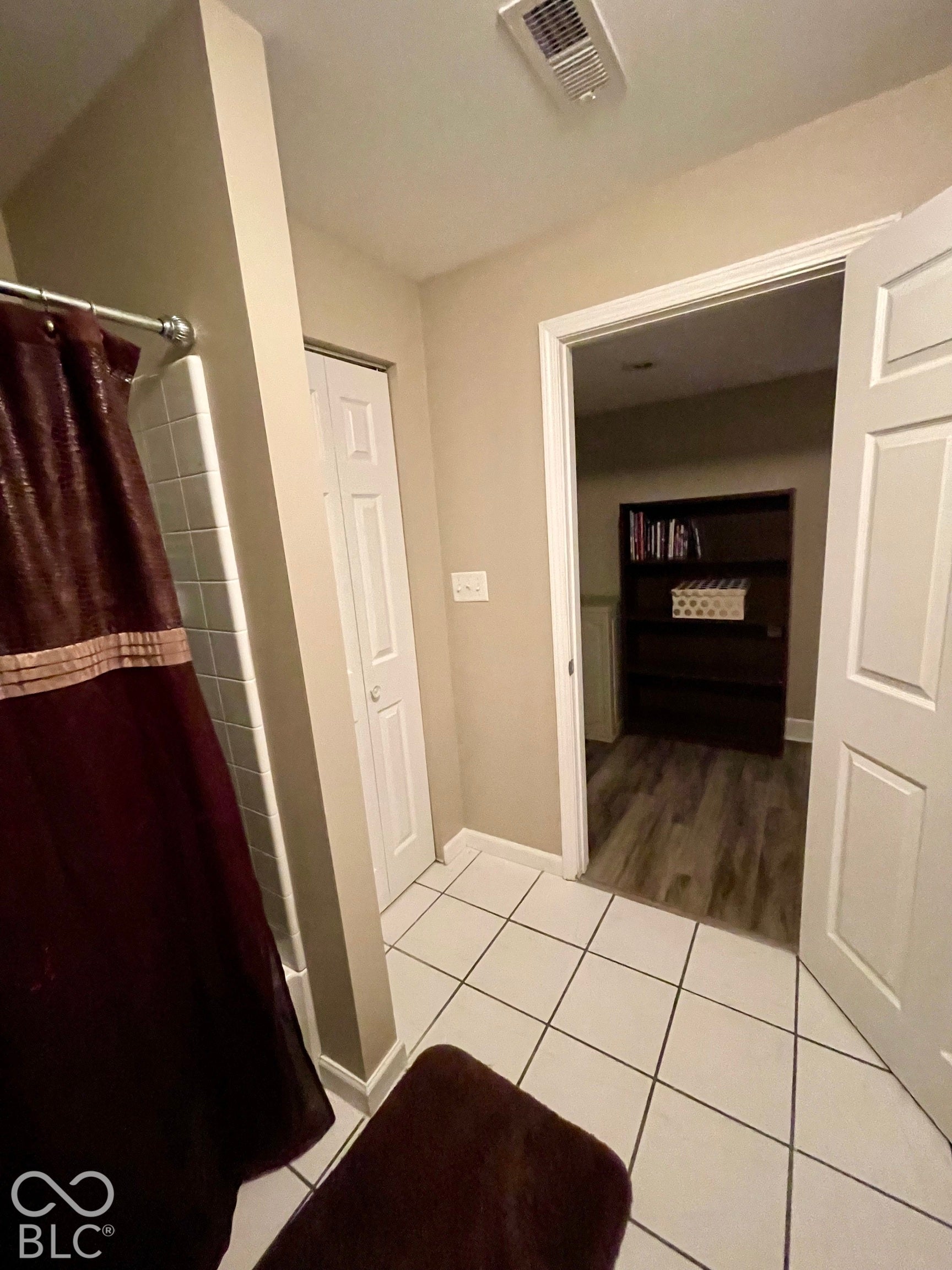 White square tile flooring, white bi-fold closet door, and a white interior door with paneling