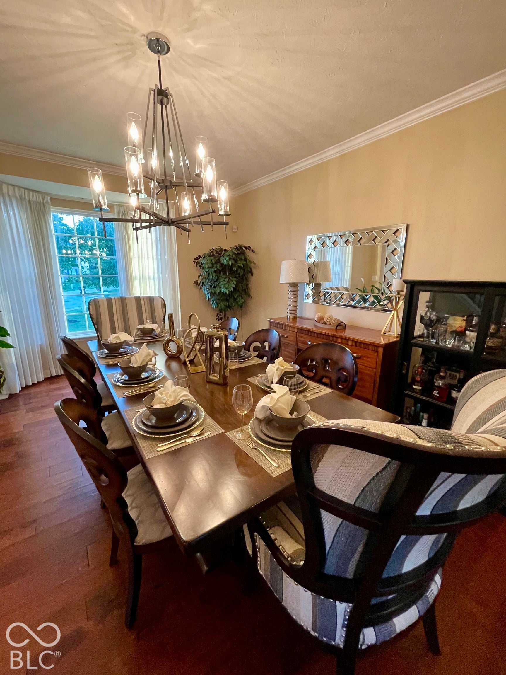 Hardwood flooring, crown molding, bay window, and a contemporary chandelier