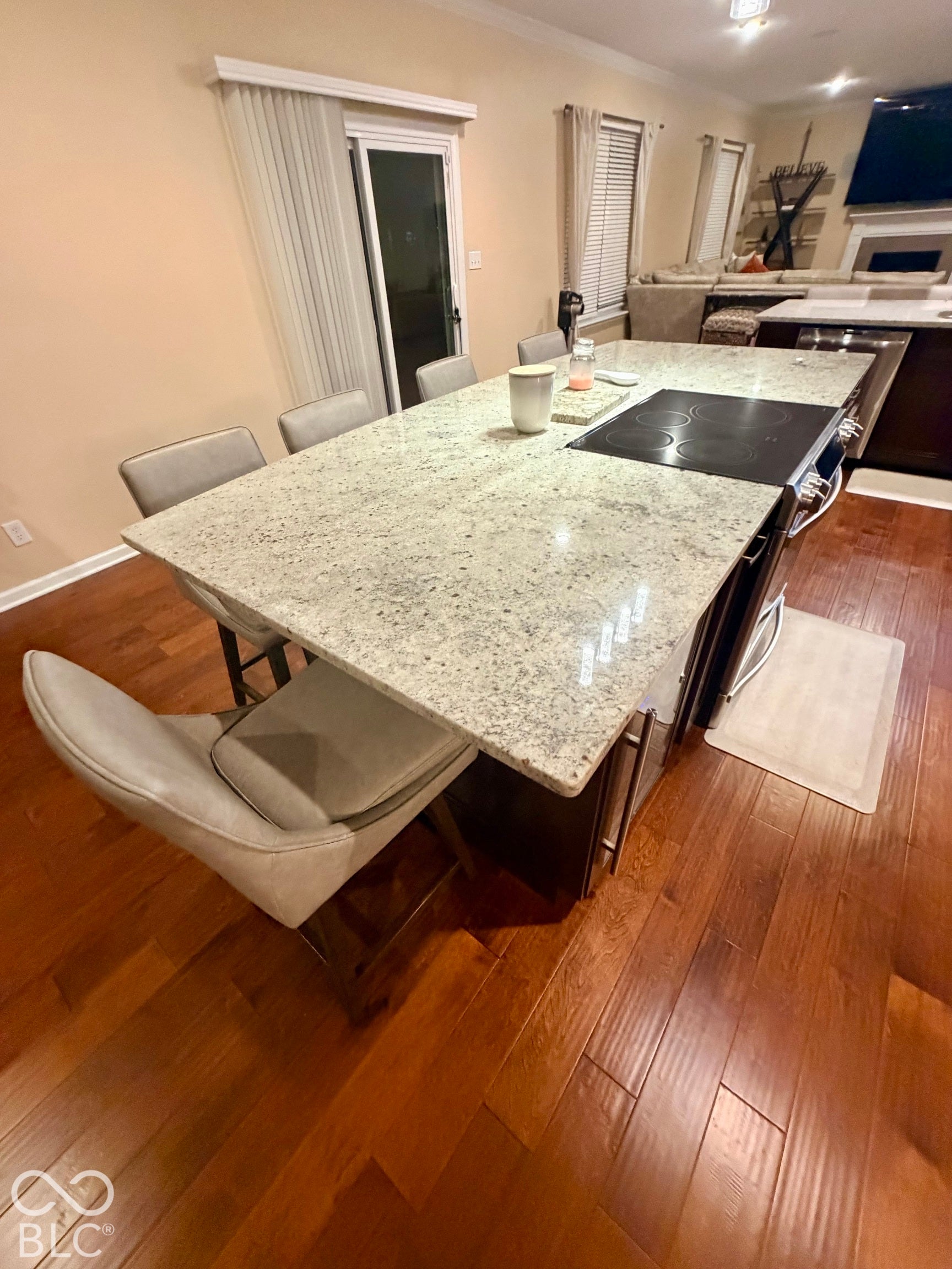 Expansive kitchen island with a light-toned countertop, built-in cooktop, and rich wood-finish flooring