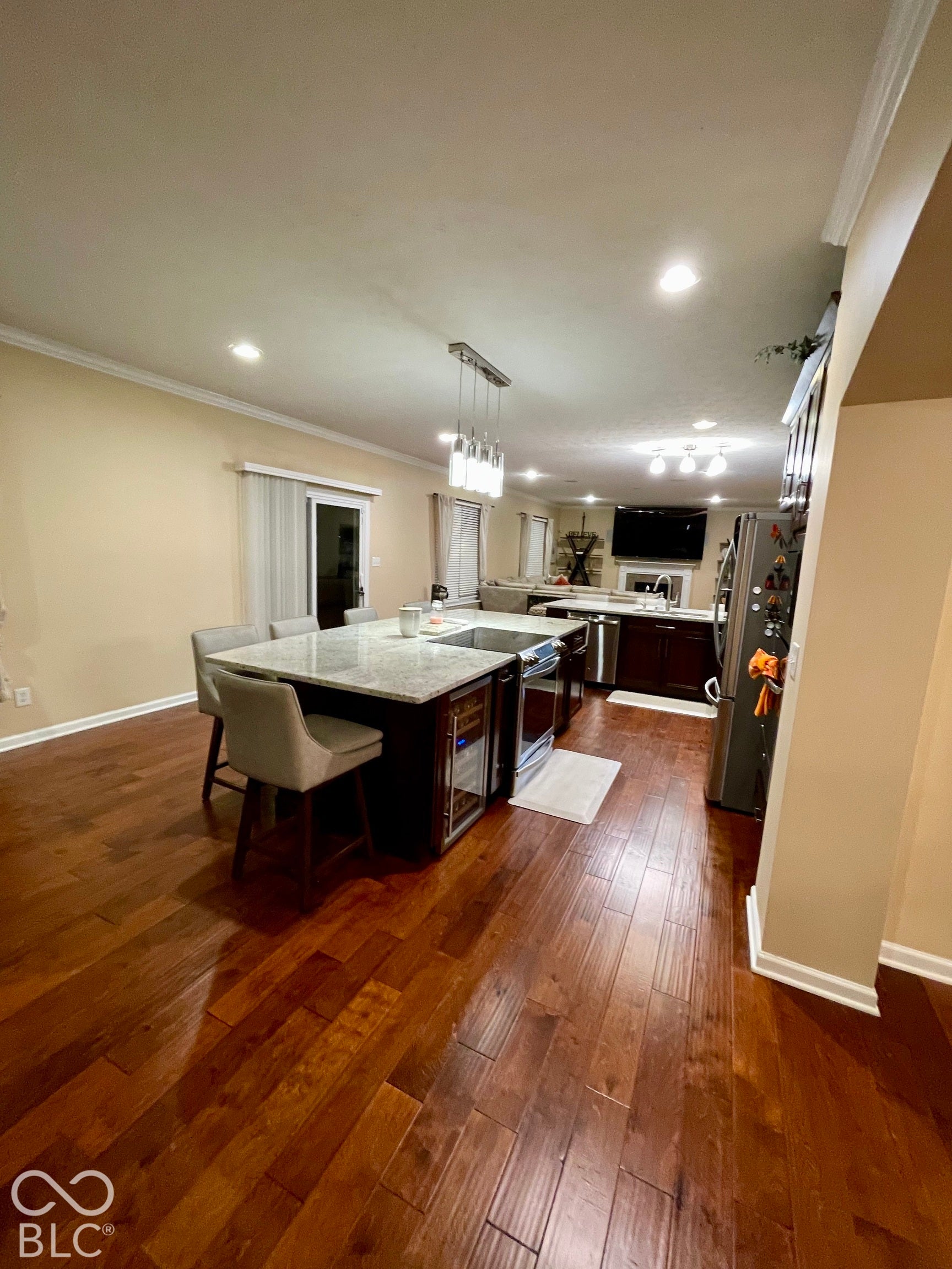 Wood-finish flooring throughout, kitchen island with built-in beverage cooler, recessed lighting, and crown molding