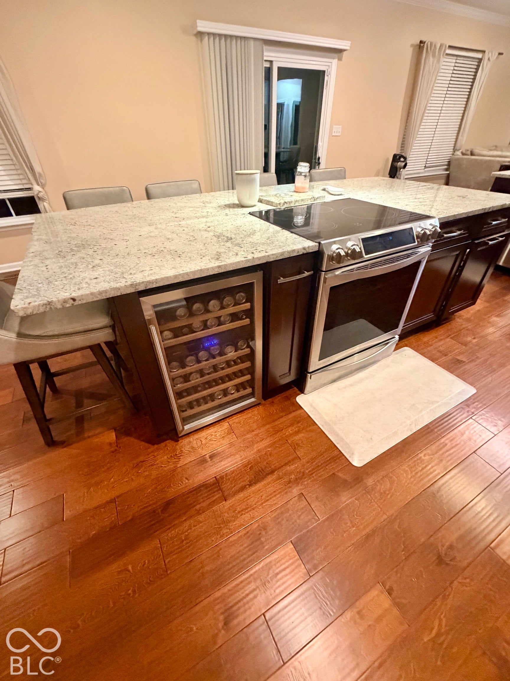 Kitchen island featuring a built-in electric range, integrated wine cooler, and light-toned stone countertop