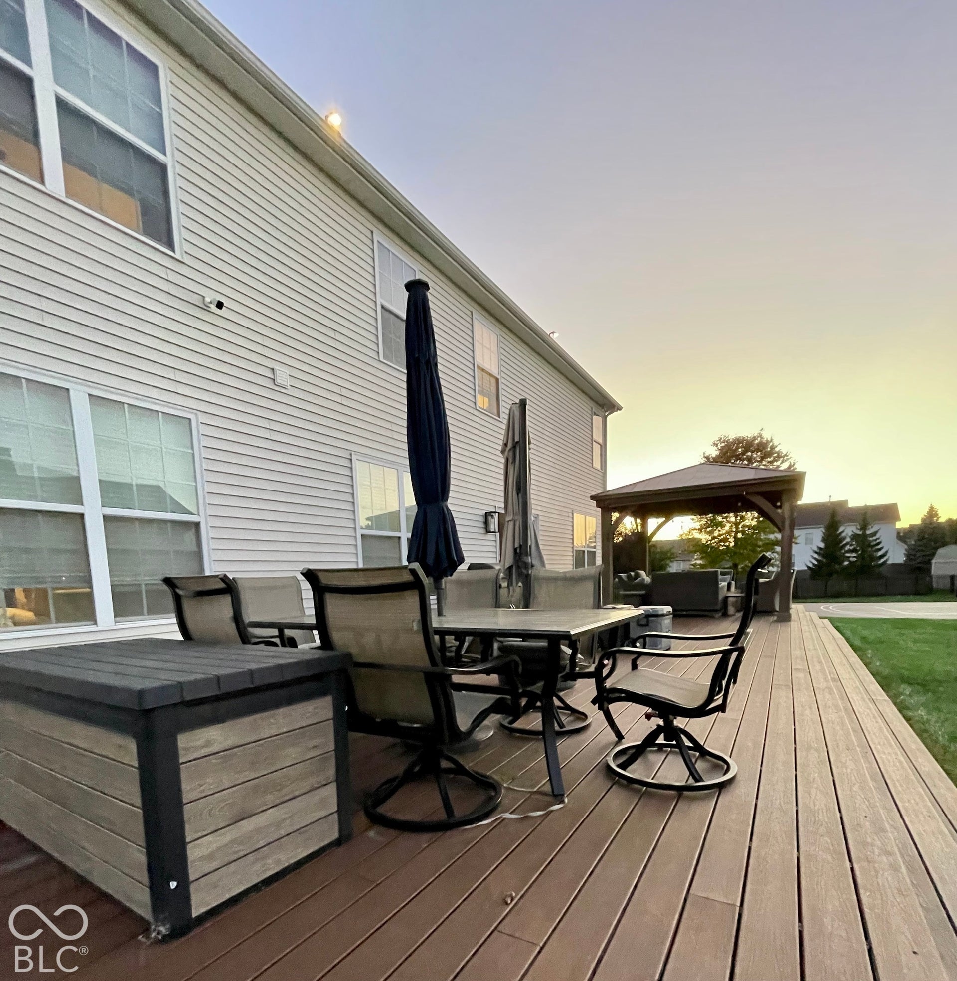 Expansive composite decking with a built-in gazebo and direct access to a manicured lawn