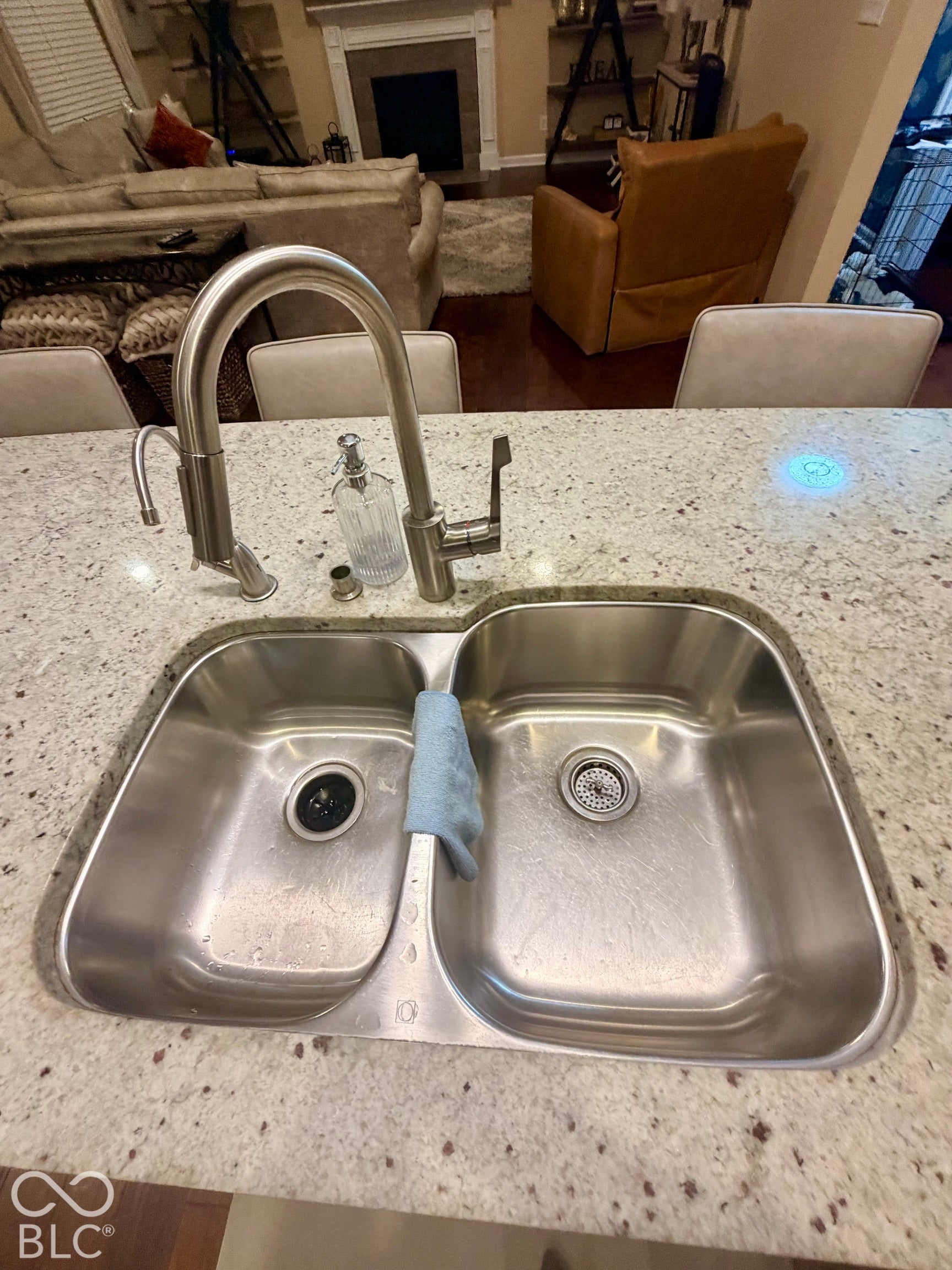 Dual basin stainless steel sink with a high-arch brushed nickel faucet, set within a speckled countertop