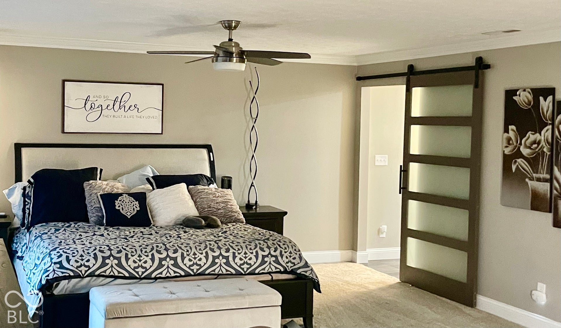 Ceiling fan with integrated lighting, neutral wall tones, and a paneled barn door with frosted glass