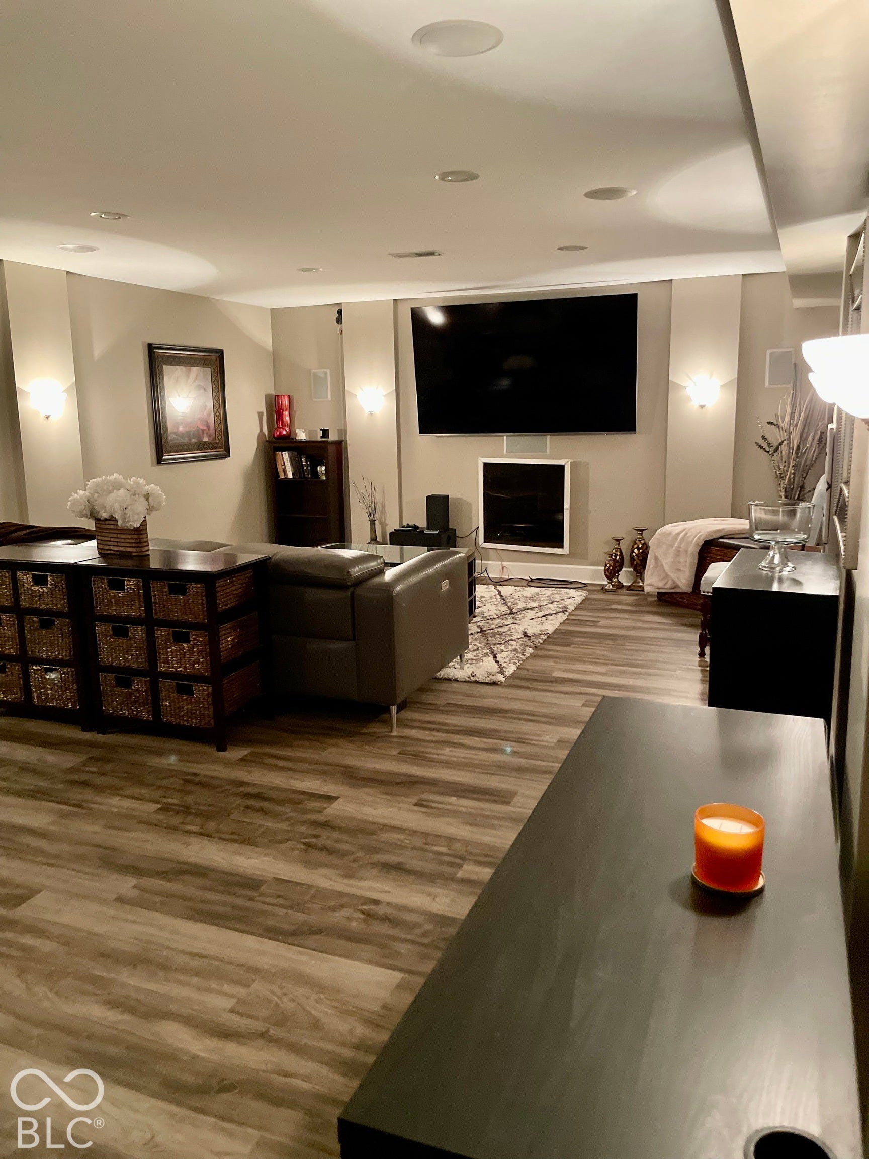 Wood-finish flooring, recessed ceiling lighting, wall-mounted display, and an integrated fireplace