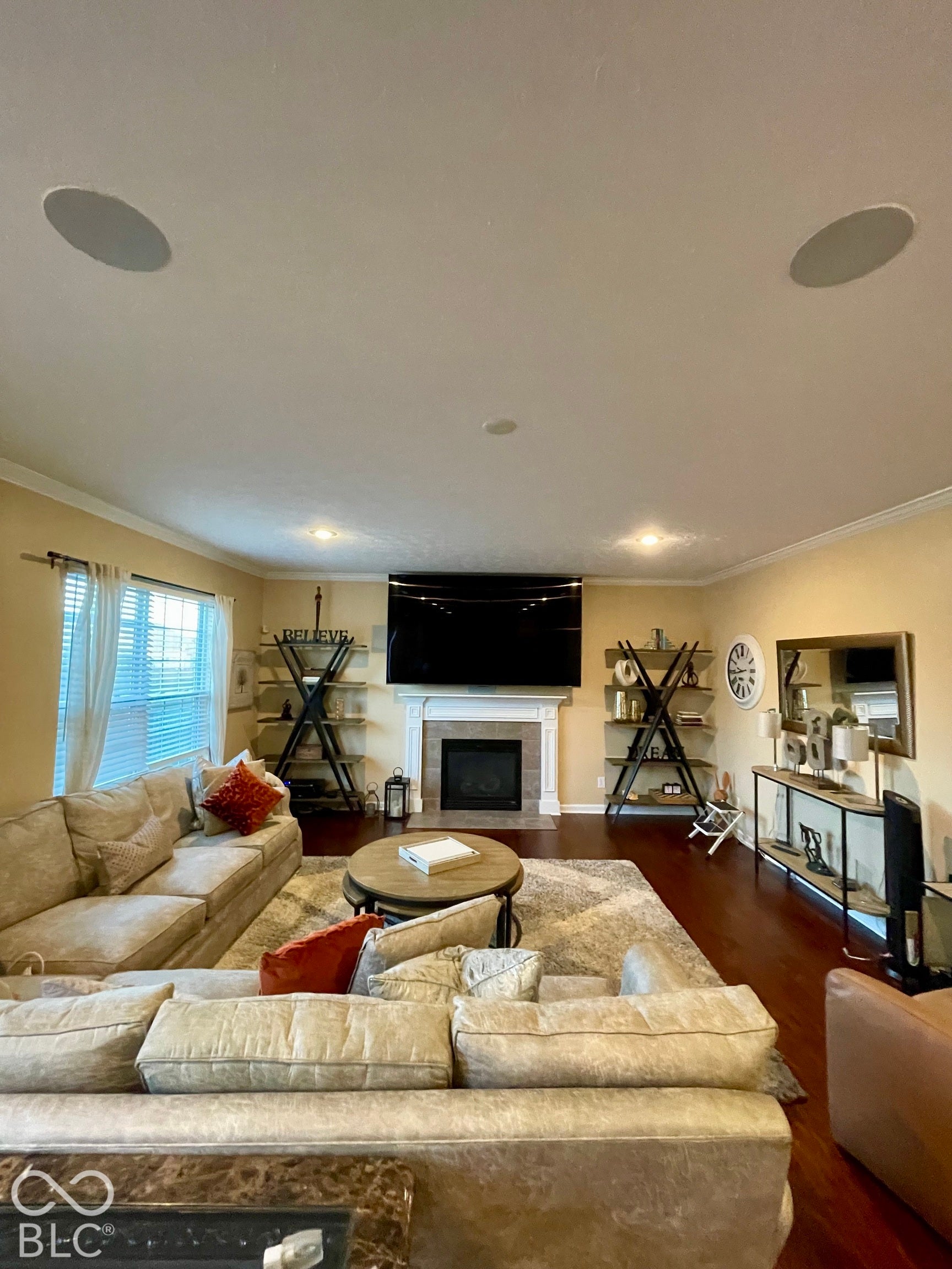 Recessed lighting, crown molding, wood-finish flooring, built-in surround sound ceiling speakers, and a fireplace with a stone surround