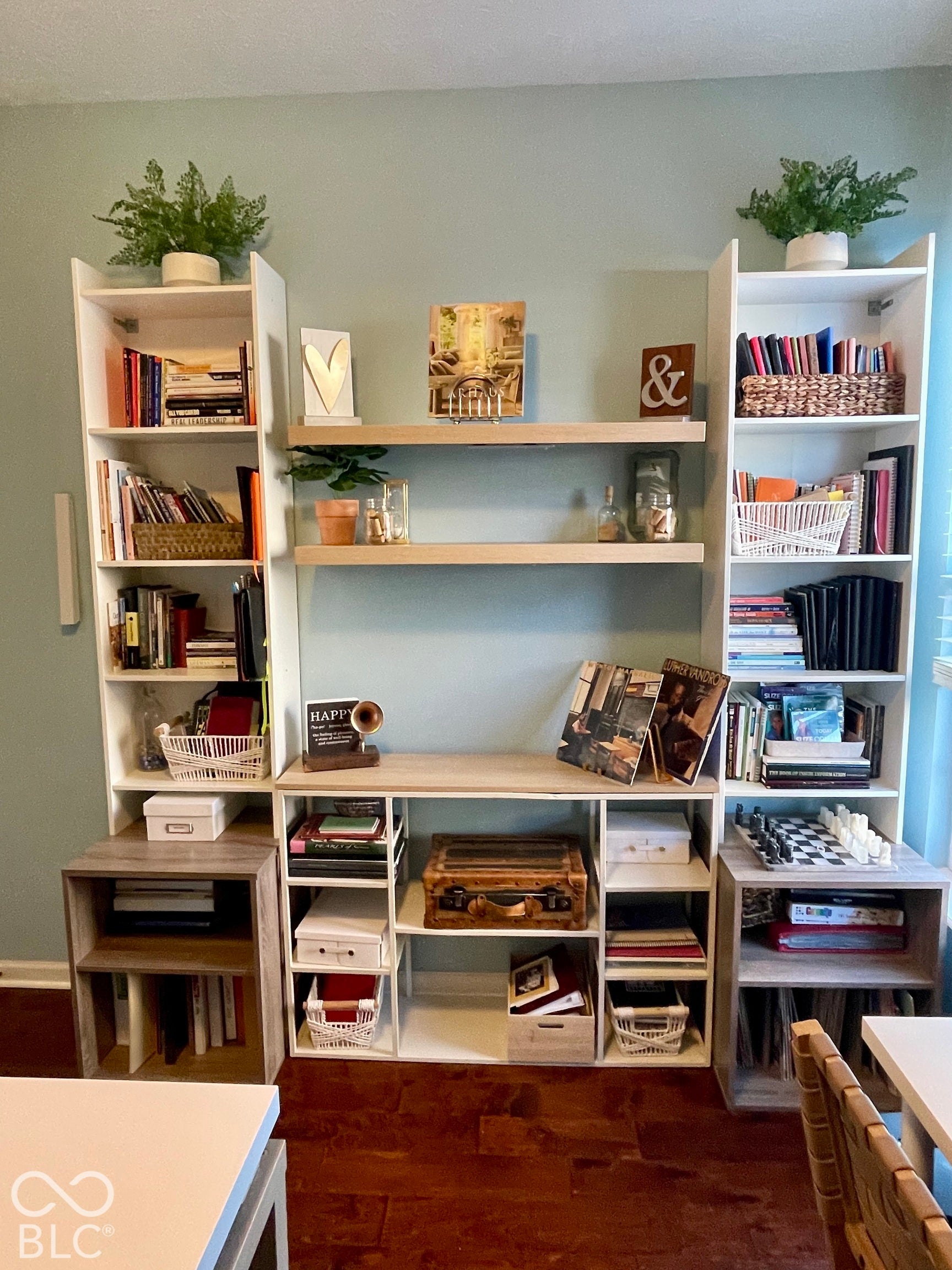 Integrated built-in shelving system featuring white and wood-finish components, open storage cubbies, and two floating shelves