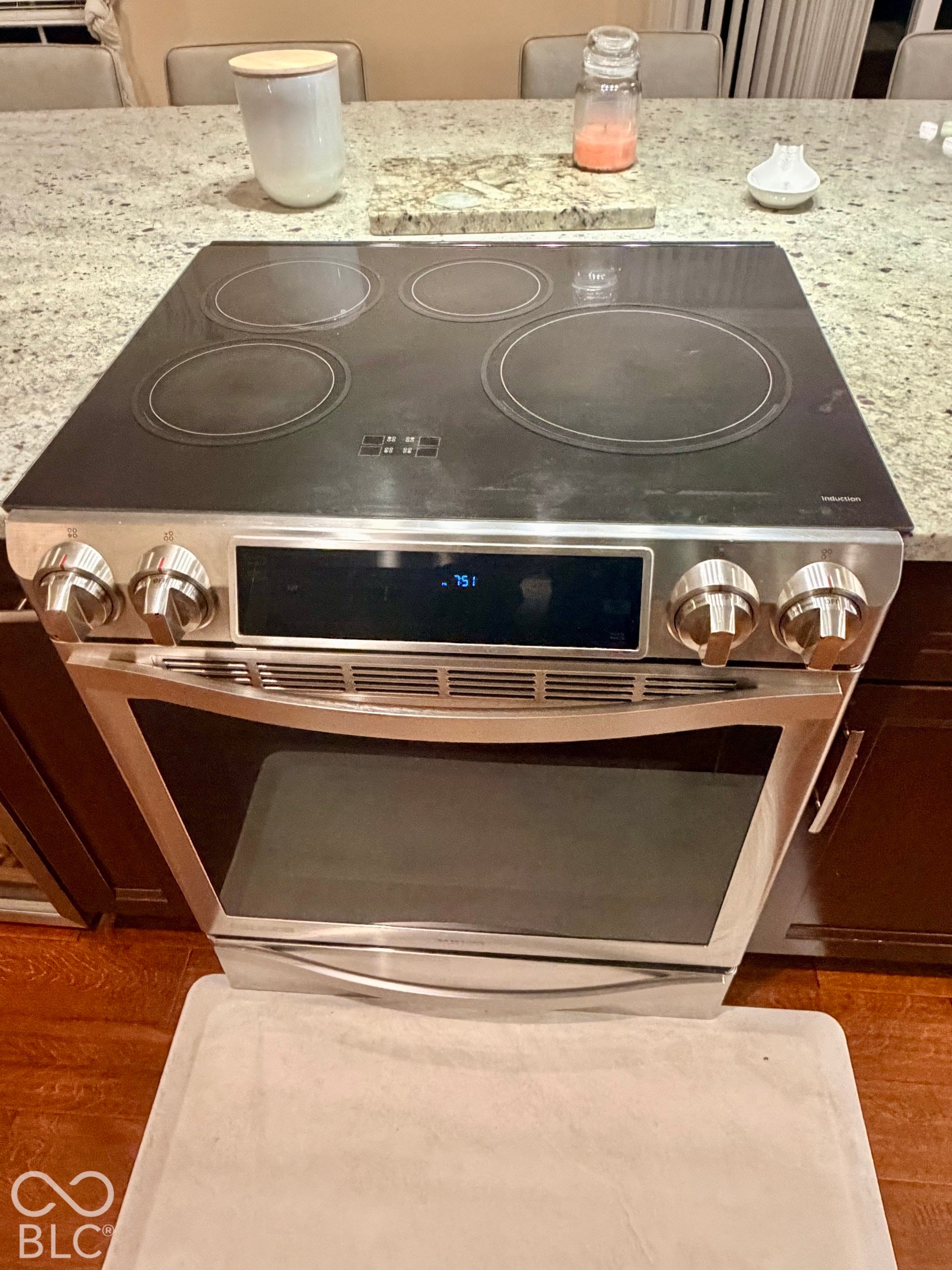 Stainless steel range with a smooth cooktop surface, integrated digital display, and knob controls