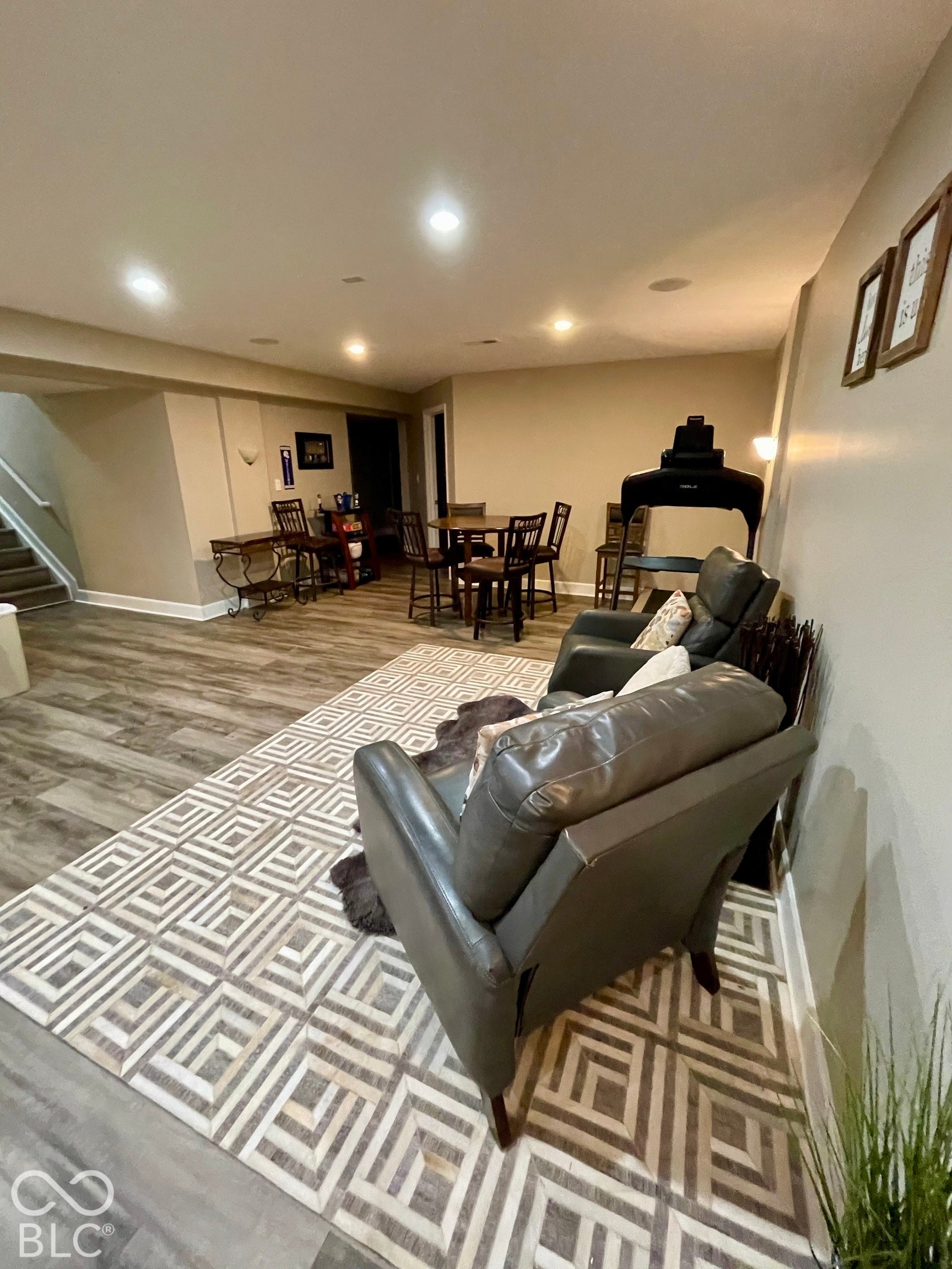 Recessed lighting, wood-finish flooring, staircase with carpeted treads, neutral wall paint, and a built-in bar area