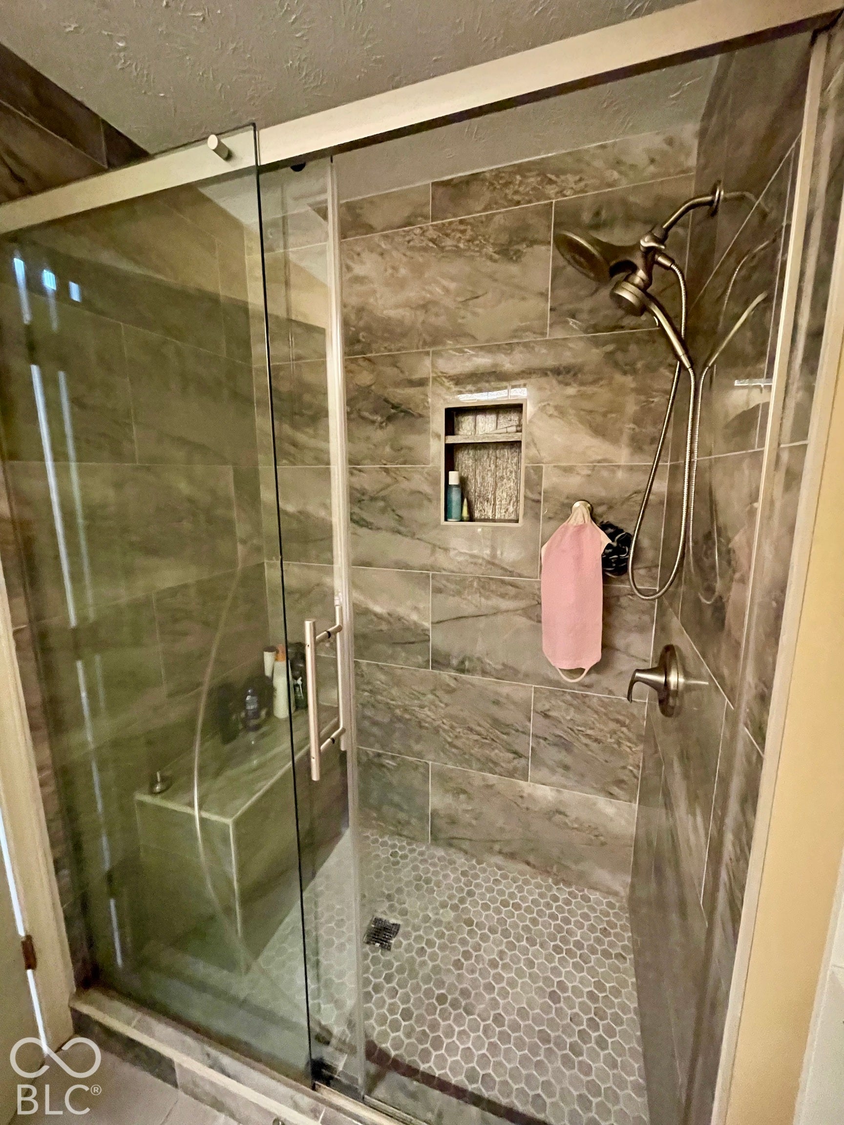 Enclosed shower with glass doors, tiled walls, built-in bench, and a recessed niche...Hall Bath