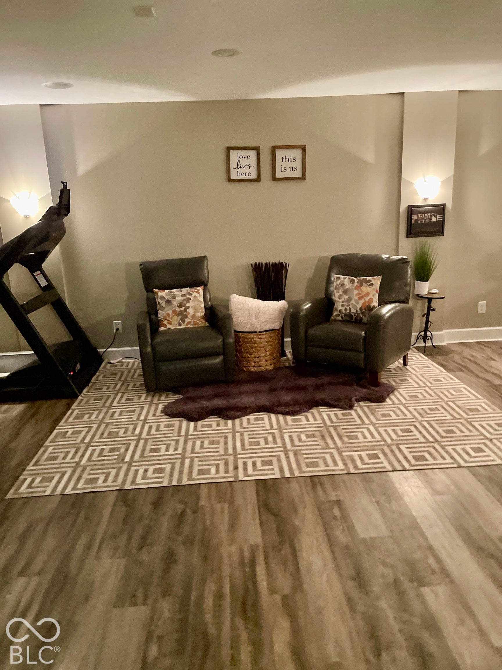 Wood-finish flooring, recessed ceiling lighting, and wall sconces illuminate this flexible living space