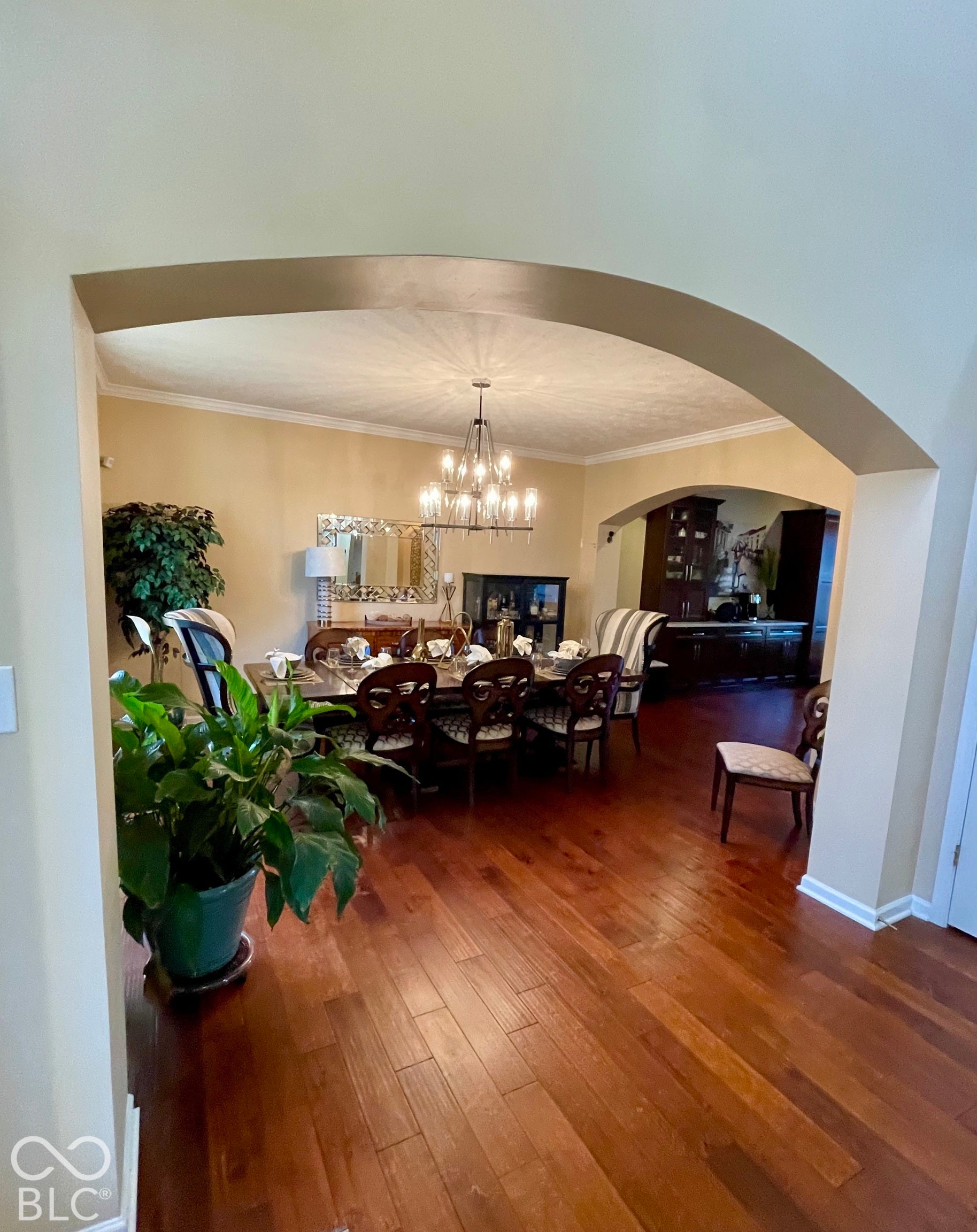 Archway entrance to a dining area featuring wood-finish flooring, an elegant chandelier light fixture, and crown molding