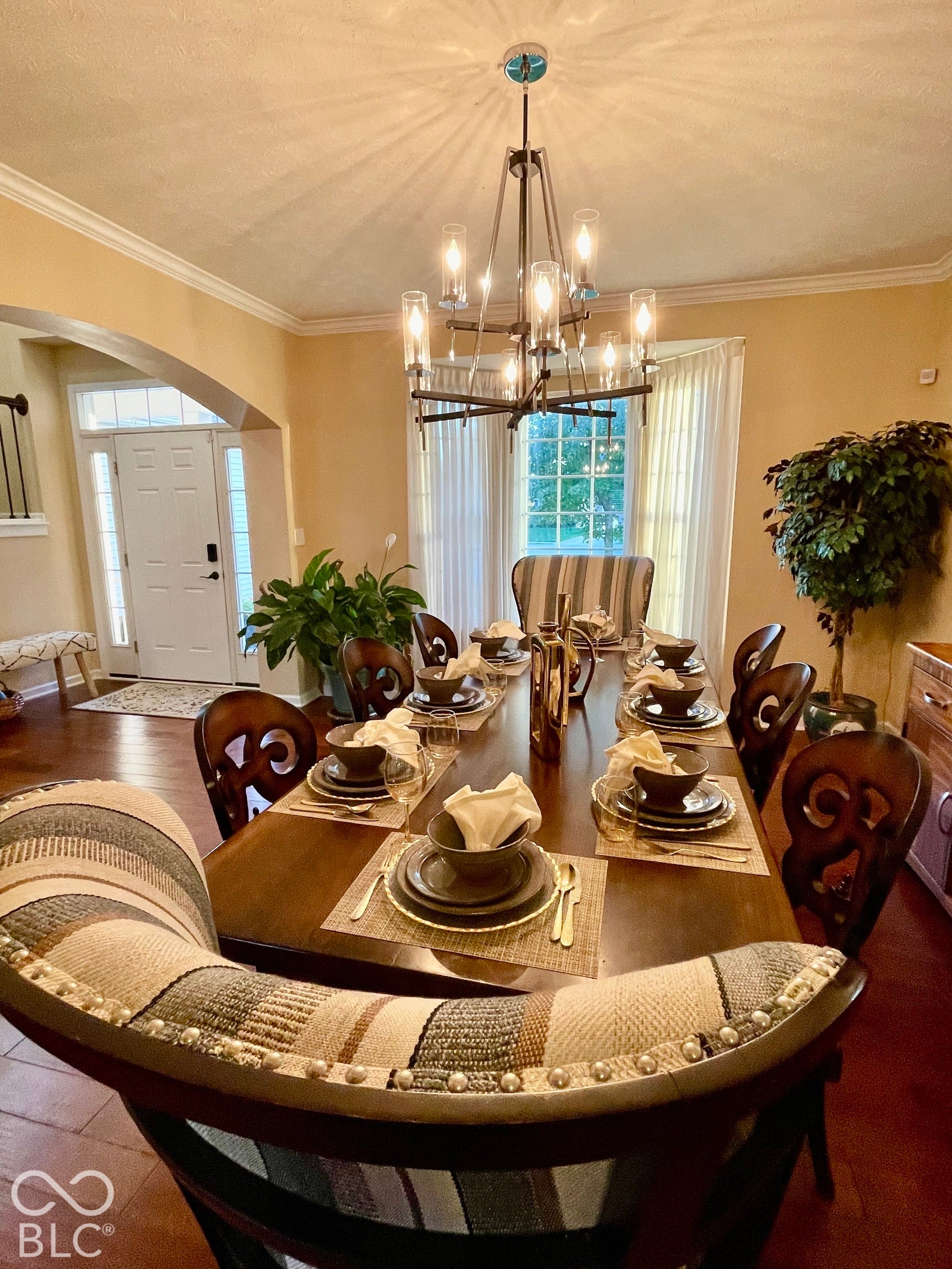 Hardwood-finish flooring, crown molding, arched entry, transom window, and a multi-light chandelier