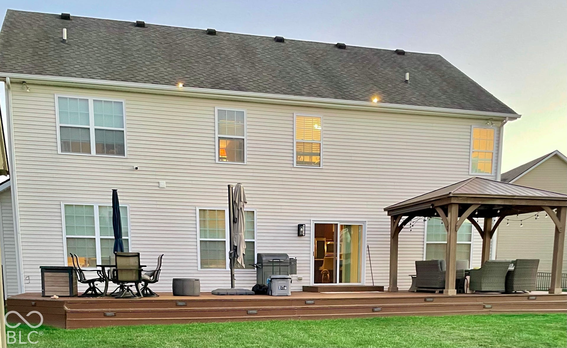 Expansive tiered deck featuring a built-in gazebo with a metal roof, multiple outdoor lighting fixtures, and a sliding glass door entry