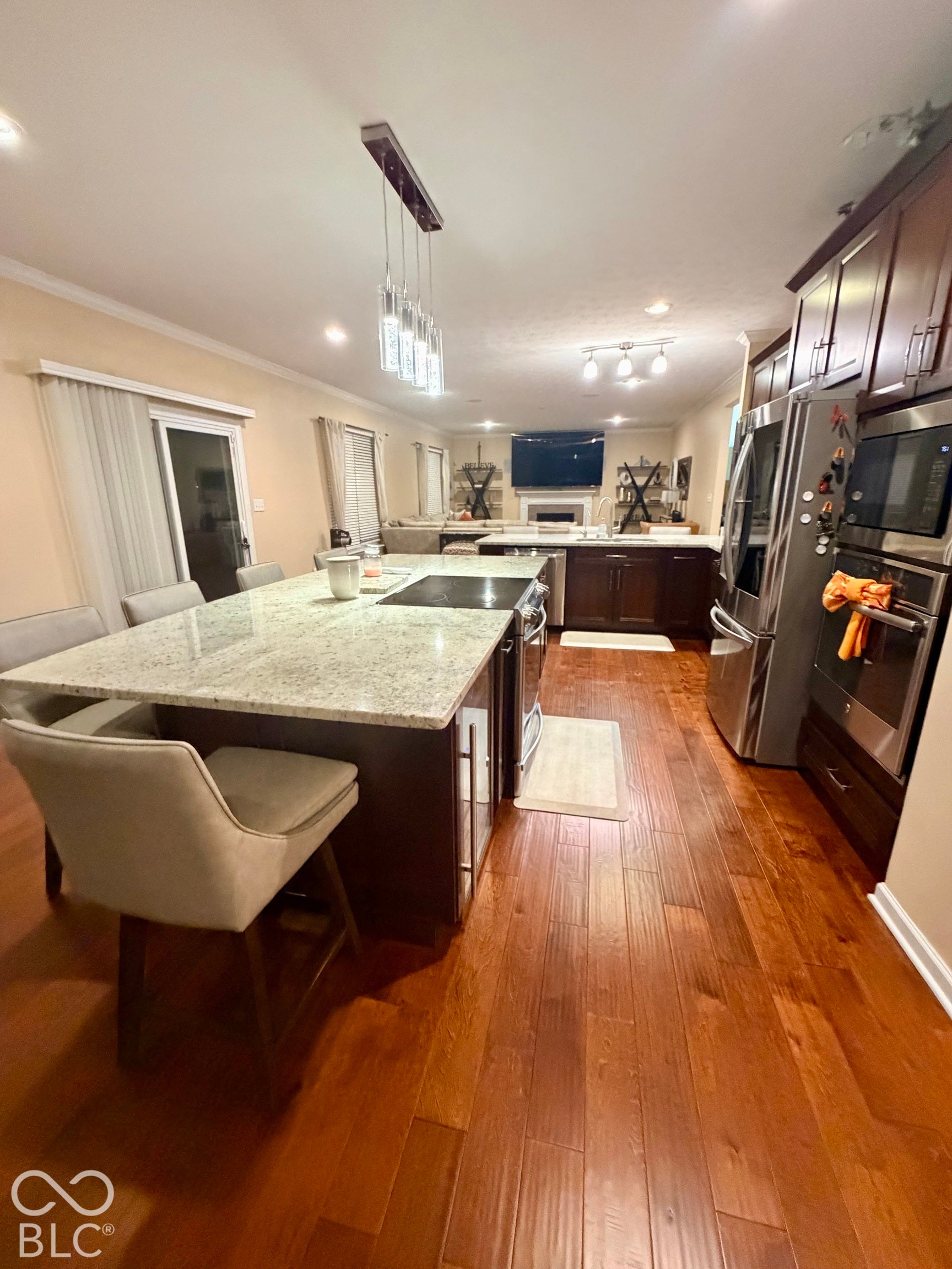 Expansive kitchen island with granite countertop, integrated cooktop, and pendant lighting