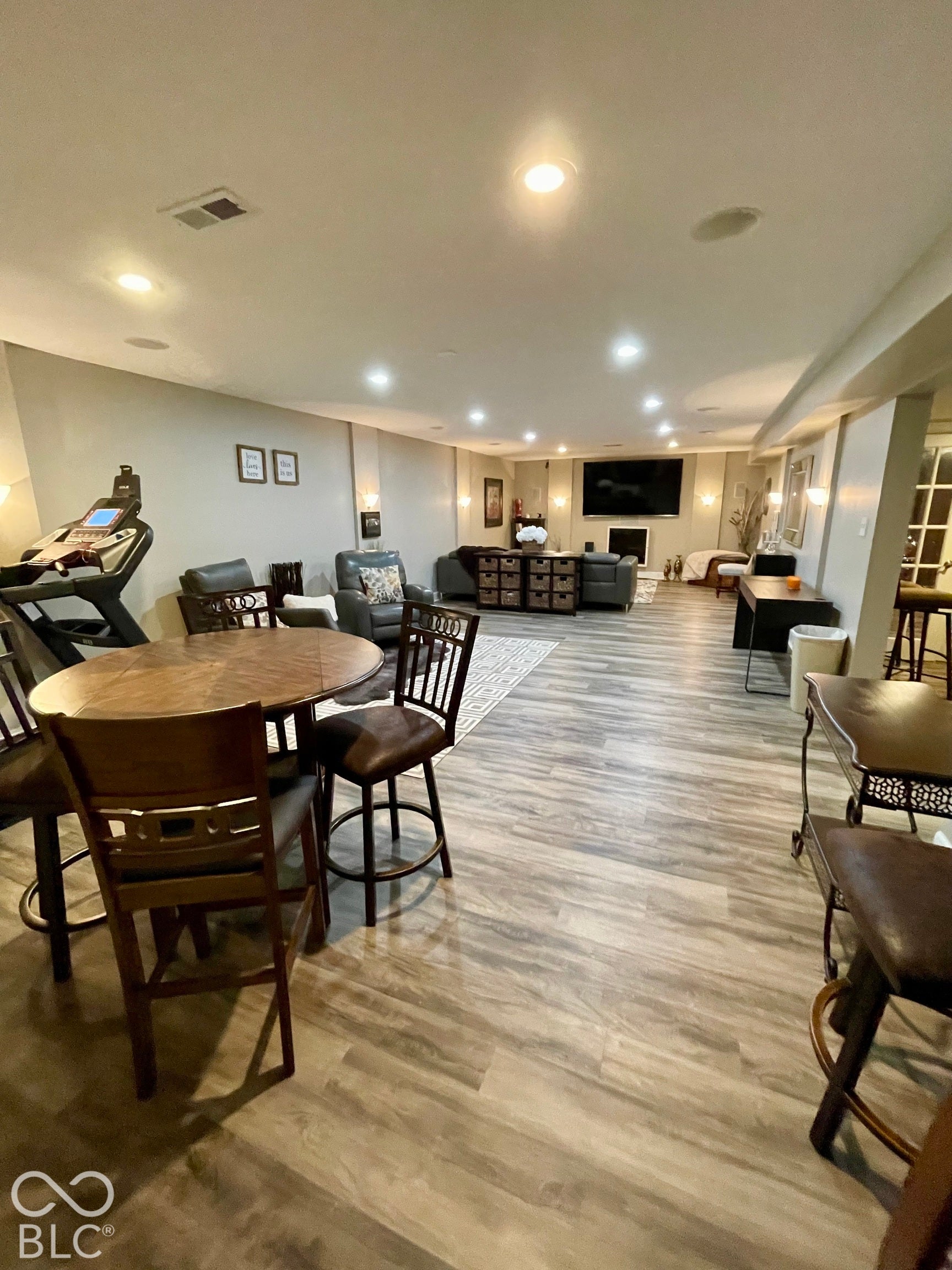 Spacious open room featuring wood-finish flooring, recessed lighting, and wall sconces