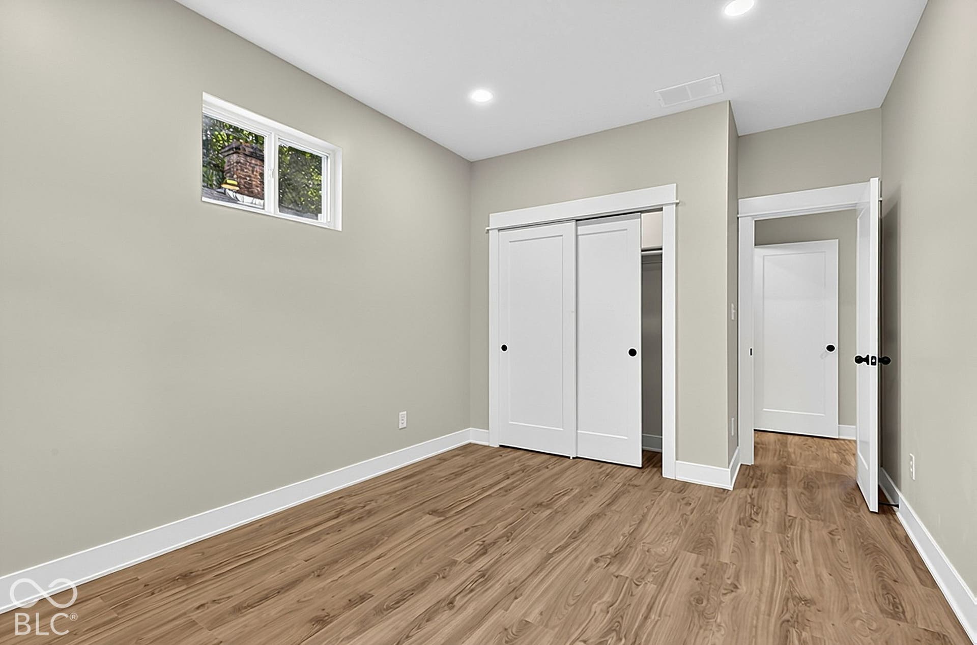 Neutral interior featuring wood-finish flooring, recessed lighting, sliding closet doors, and multi-panel interior doors