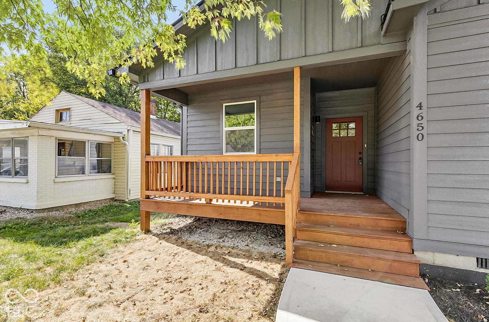 Gray siding exterior featuring a wooden front porch, a multi-pane front door, and vertical board-and-batten accent siding