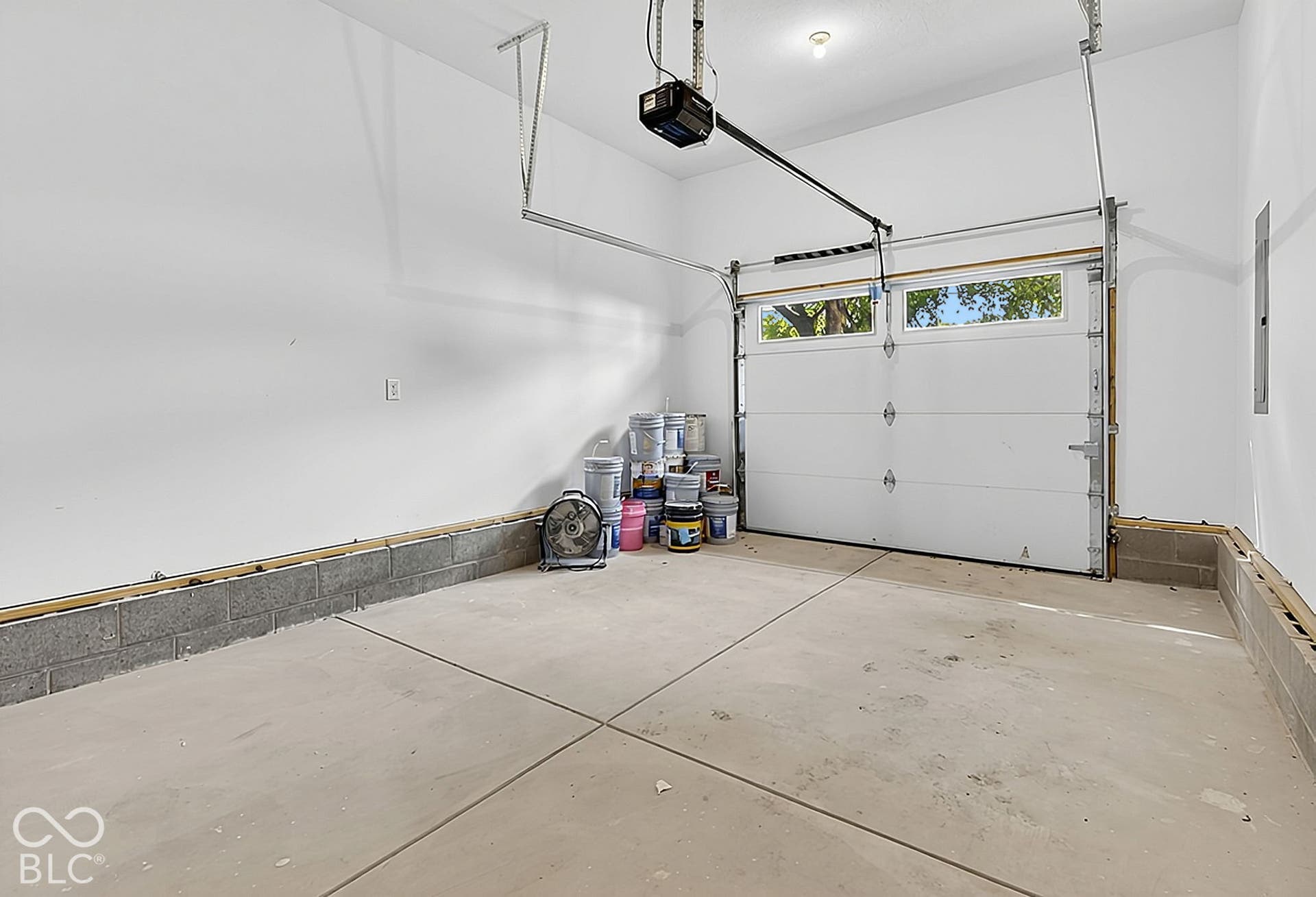 Garage space featuring a concrete floor, white walls, and a sectional overhead door with glass inserts