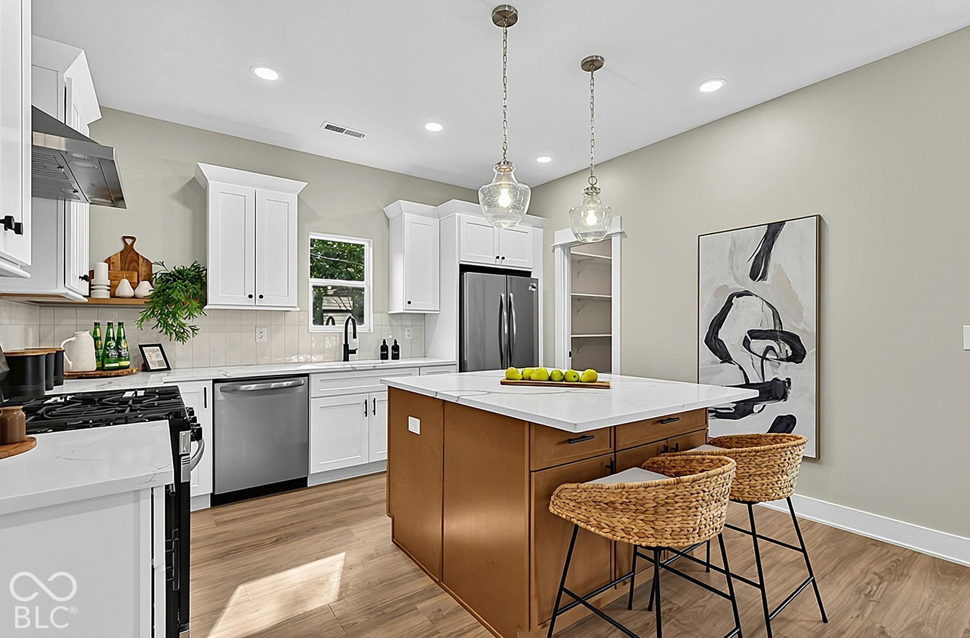 Kitchen featuring white cabinetry, wood-finish flooring, a central island with a solid surface countertop, stainless steel appliances, and dual glass pendant lights
