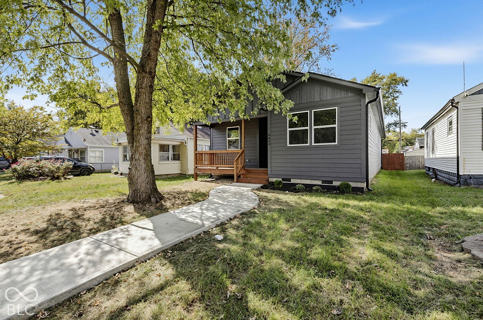 Dark-toned horizontal lap siding exterior featuring a front-facing wood deck and a paved concrete walkway
