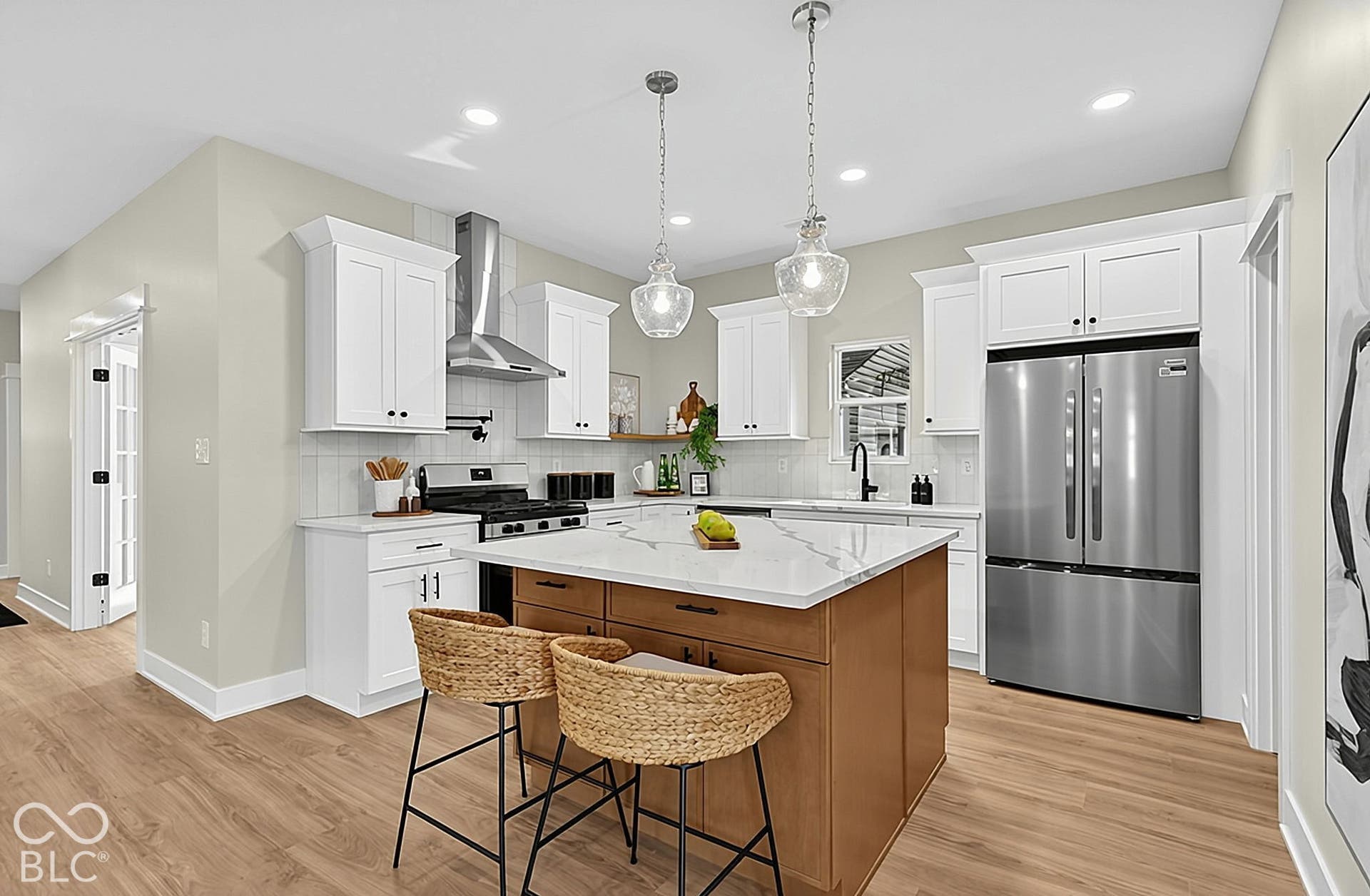 Kitchen featuring white shaker-style cabinetry, a contrasting wood-finish center island with a quartz countertop, stainless steel appliances, and pendant lighting