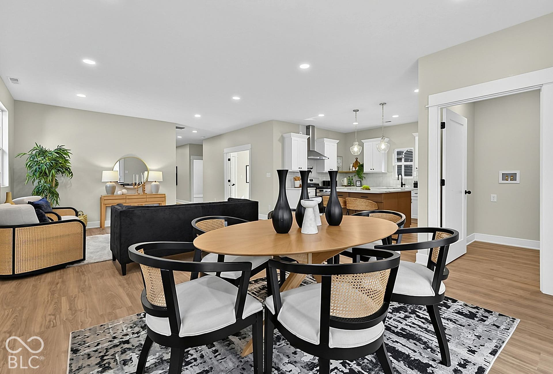 Open-concept interior featuring wood-finish flooring, recessed lighting, and a kitchen equipped with white cabinetry and a stainless steel range hood