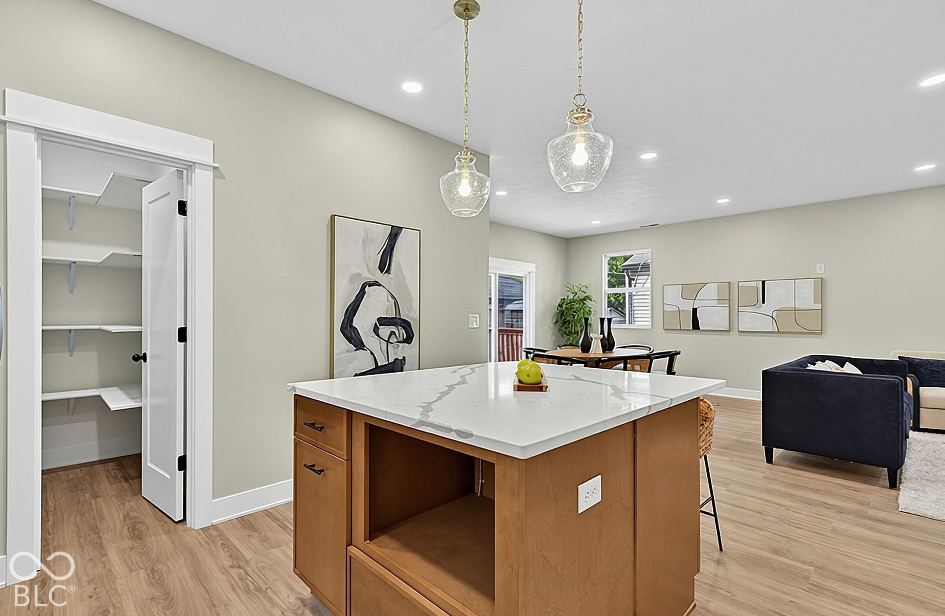Kitchen island with stone-finish countertop, walk-in pantry with built-in shelving, glass pendant lighting, recessed ceiling lights, and wood-finish flooring