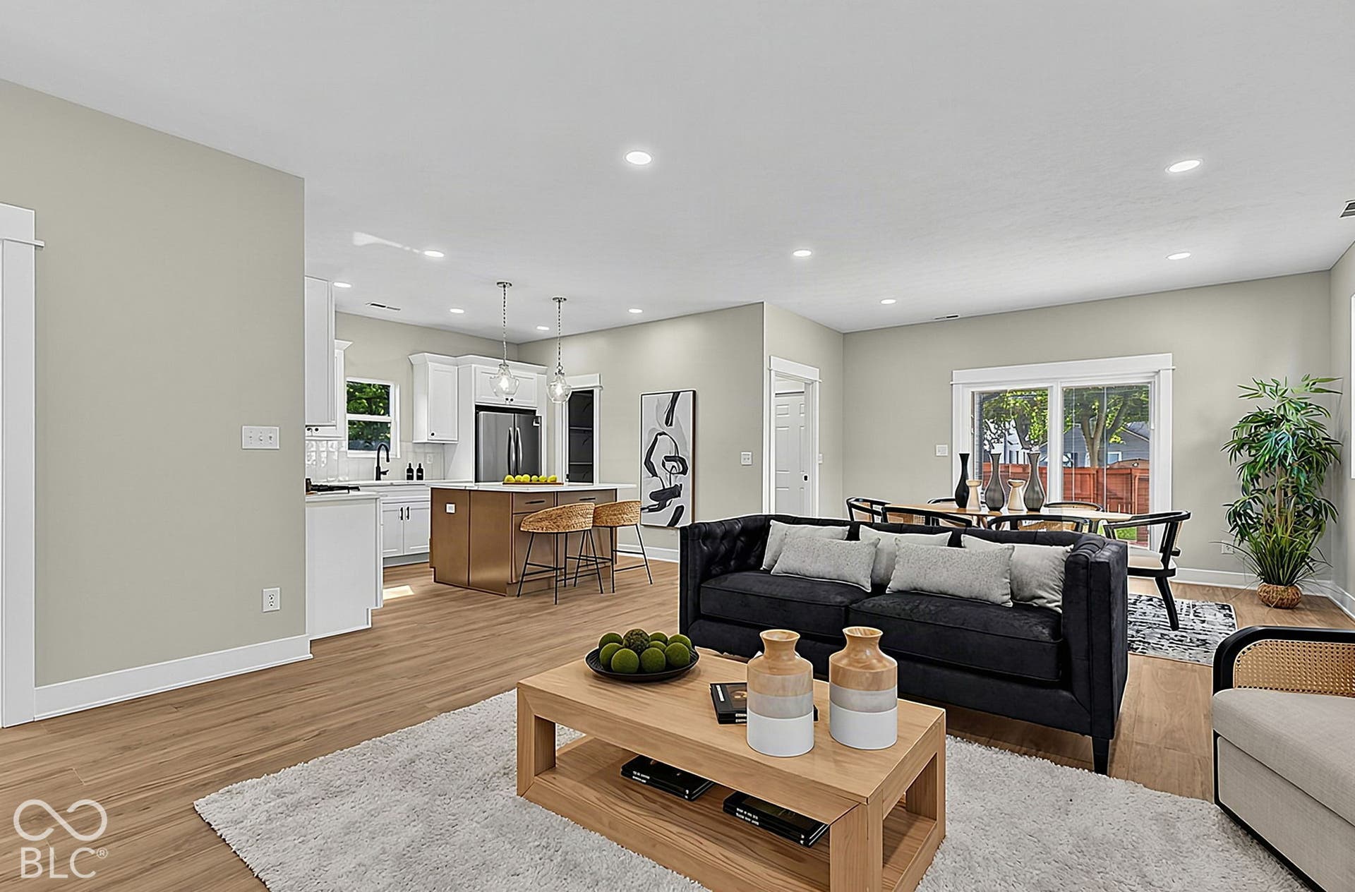 Open-concept floor plan featuring wood-finish flooring, recessed lighting, white cabinetry, a center island, and sliding glass doors