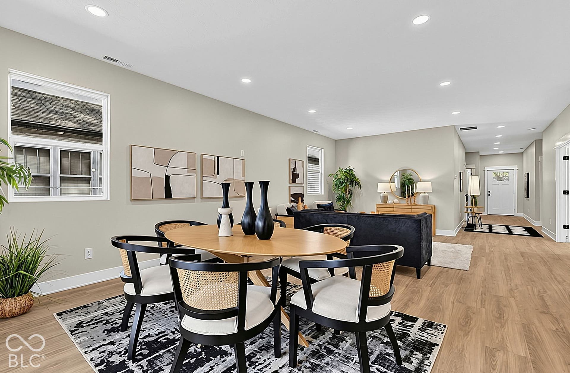 Open-concept space with wood-finish flooring, recessed lighting, and windows with white casings